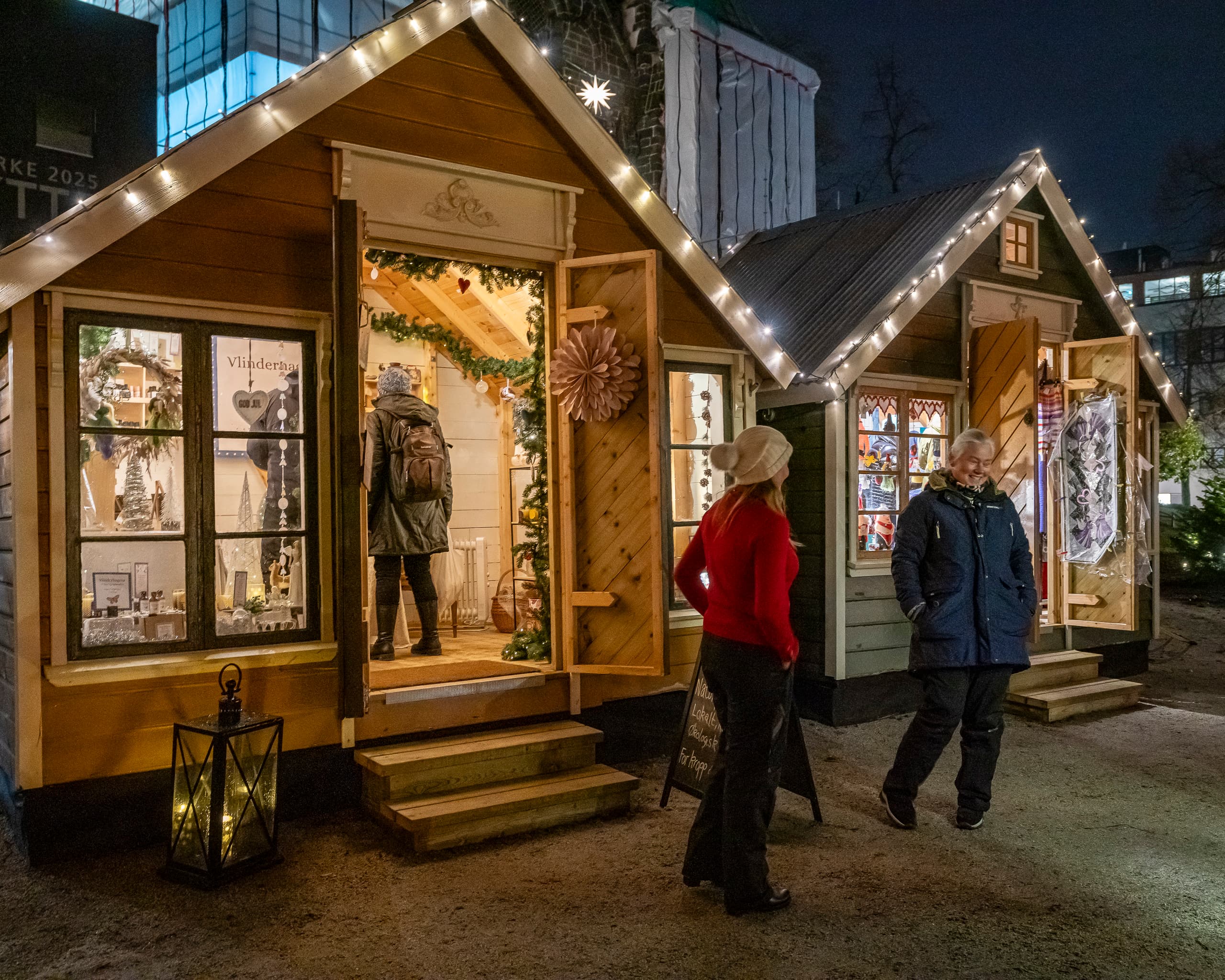 Christmas market stalls with two people outside and 1 person inside