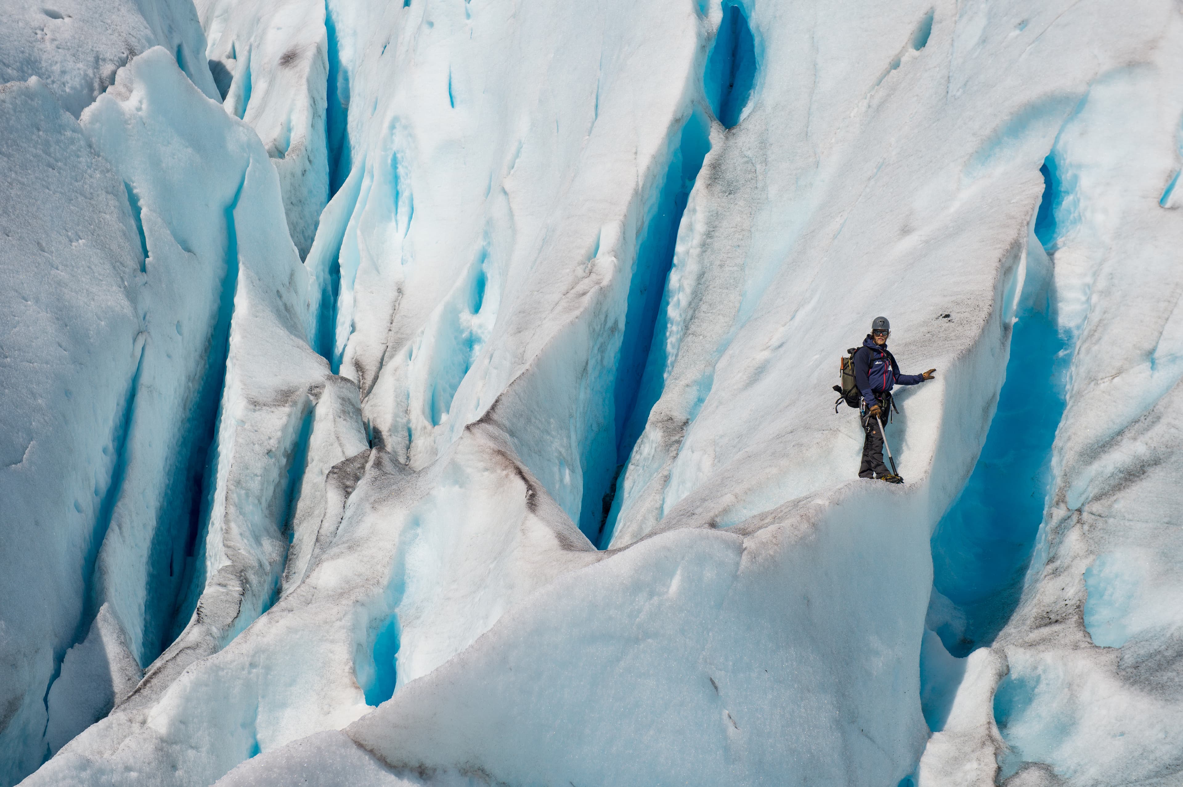 En person som står på Nigardsbreen med hjelm og ishakke.