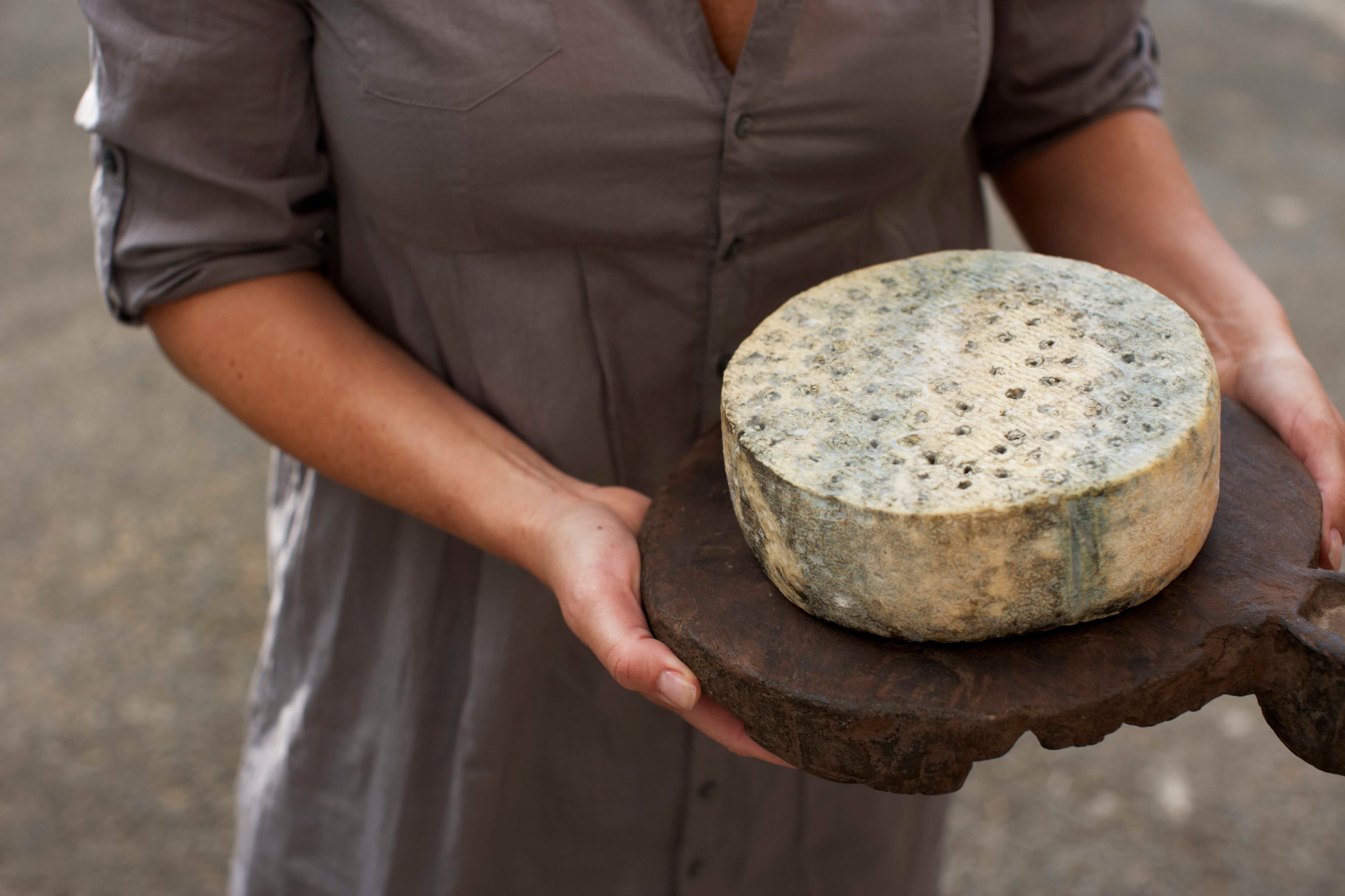Kvinne holder osten kraftkar på en trefjøl