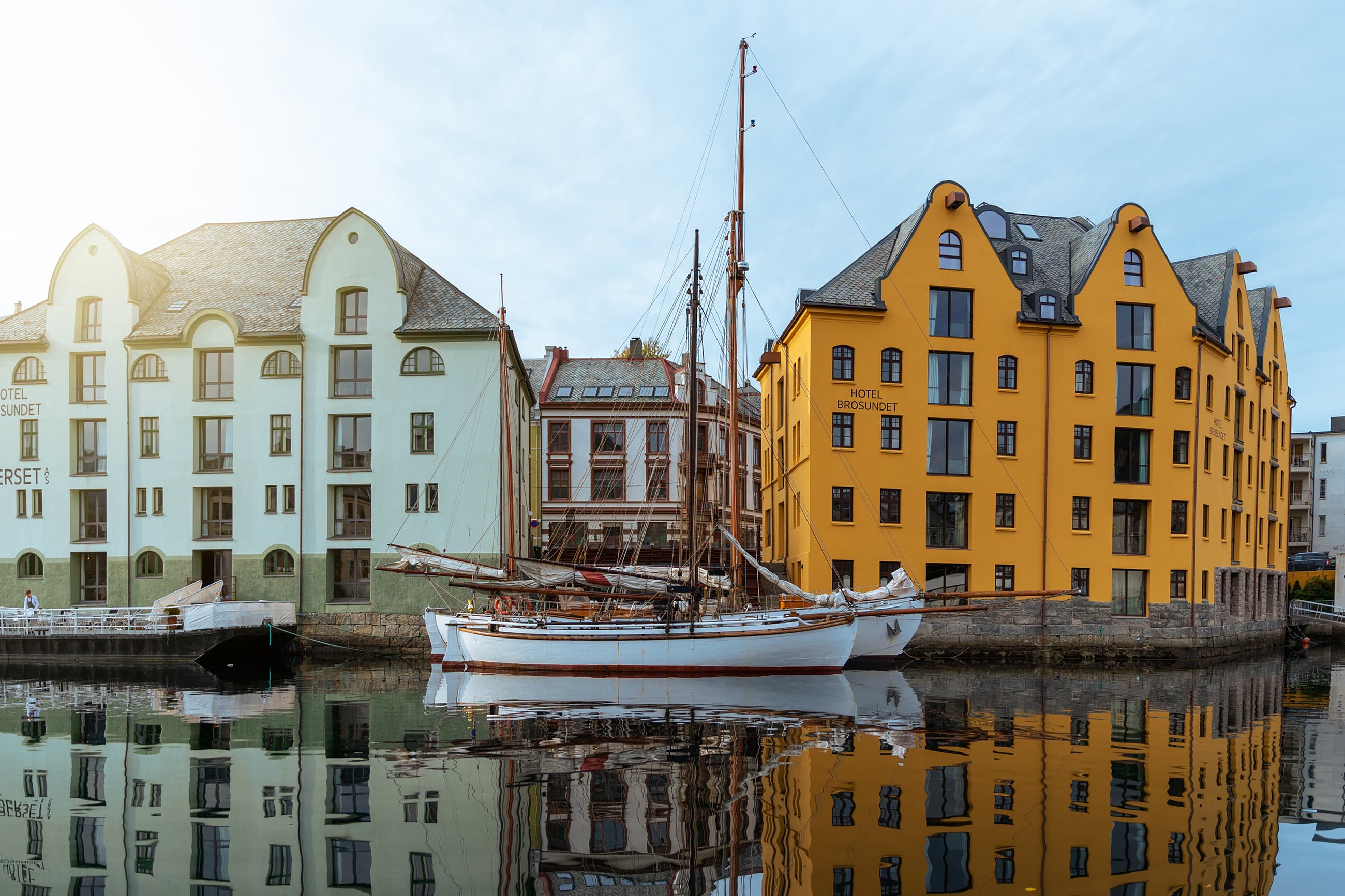 Båter ligger til kai ved fargerike hotel i Brosundet i Ålesund.