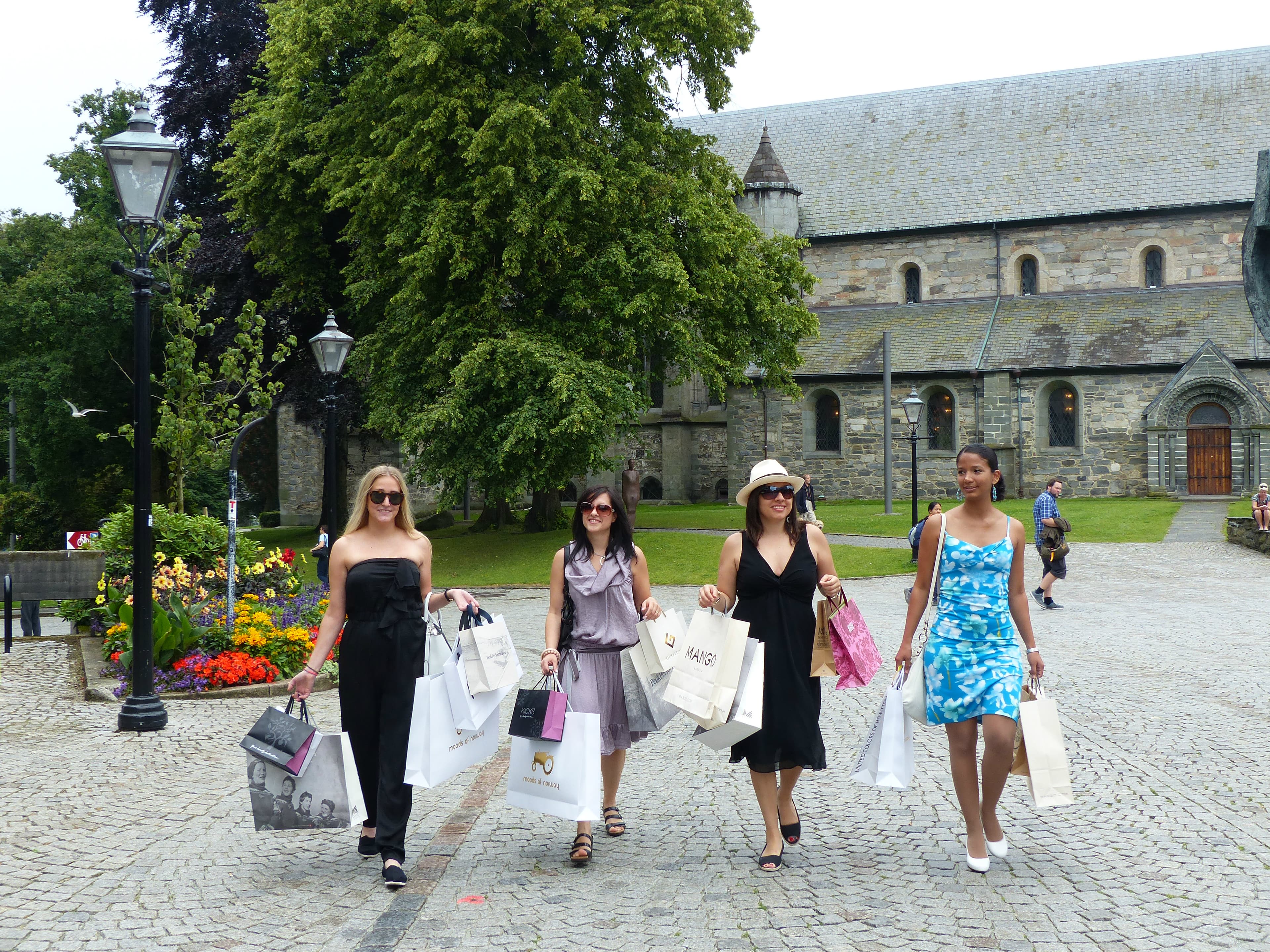 Fire damer går med handleposer over Domkirkeplassen i Stavanger.