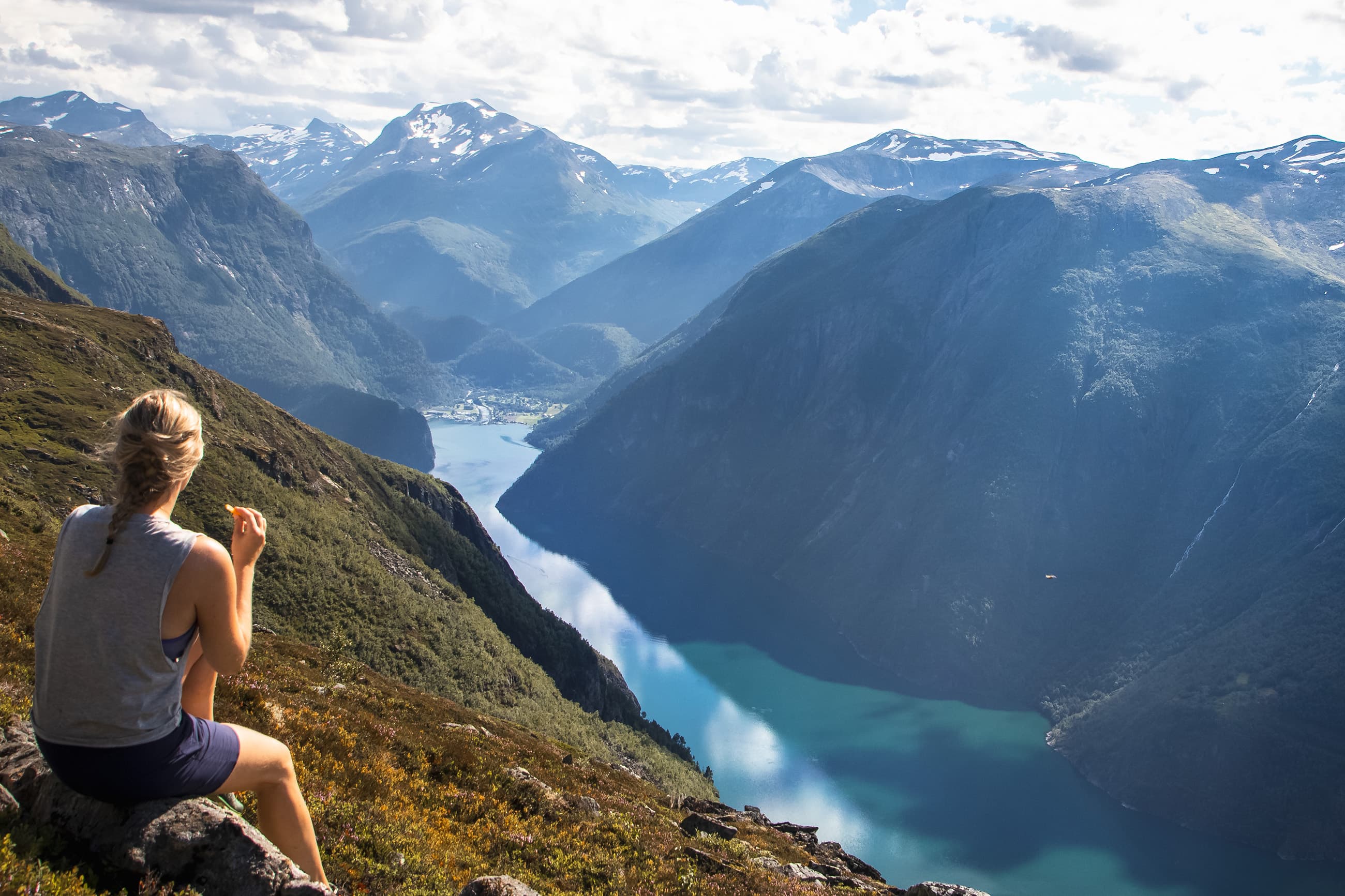 Person sitter på fjellet Heggura og ser på utsikta innover tafjorden og Tafjordfjella