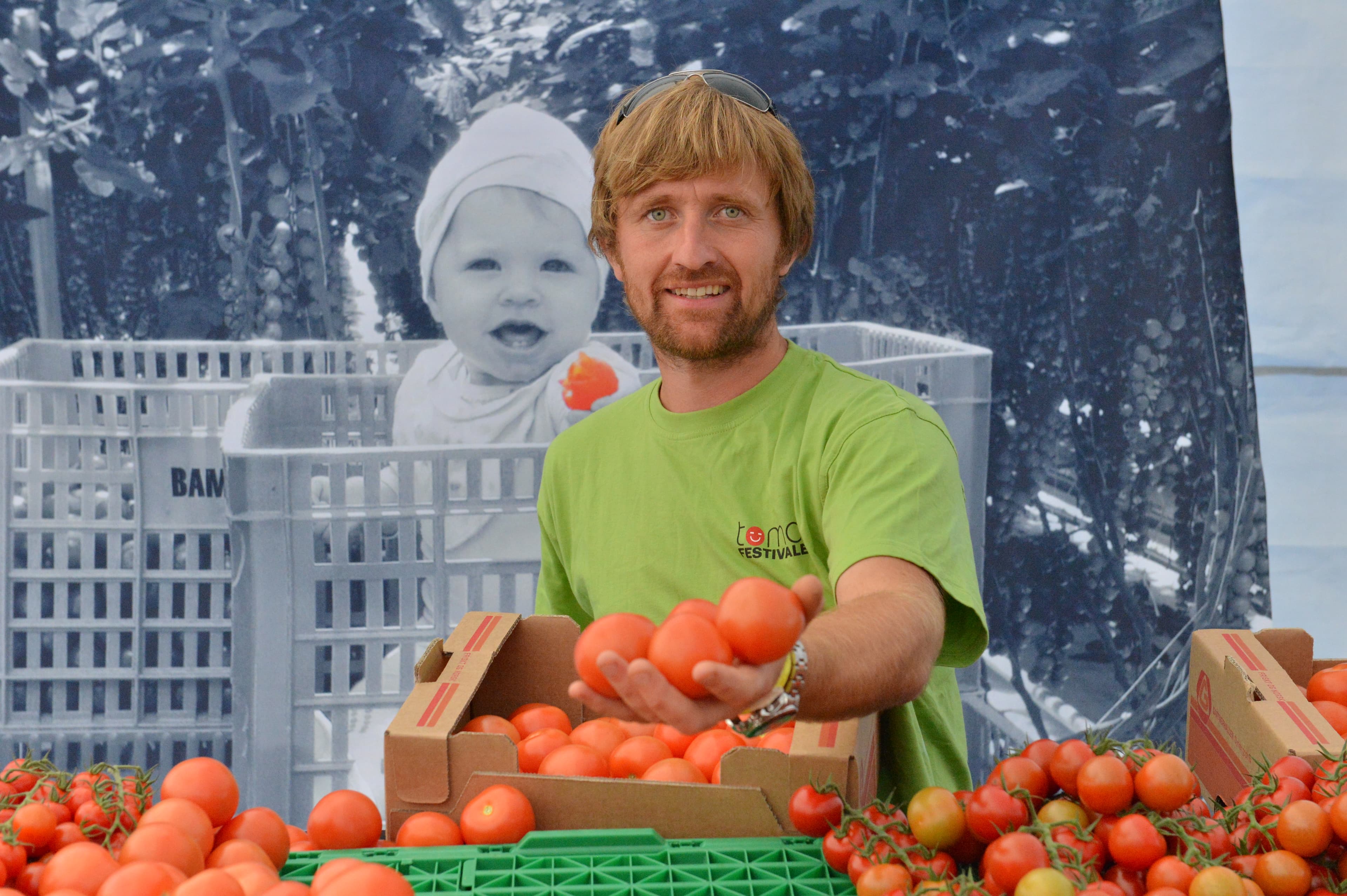 Mann med tomater i hånden og i kasser foran seg.