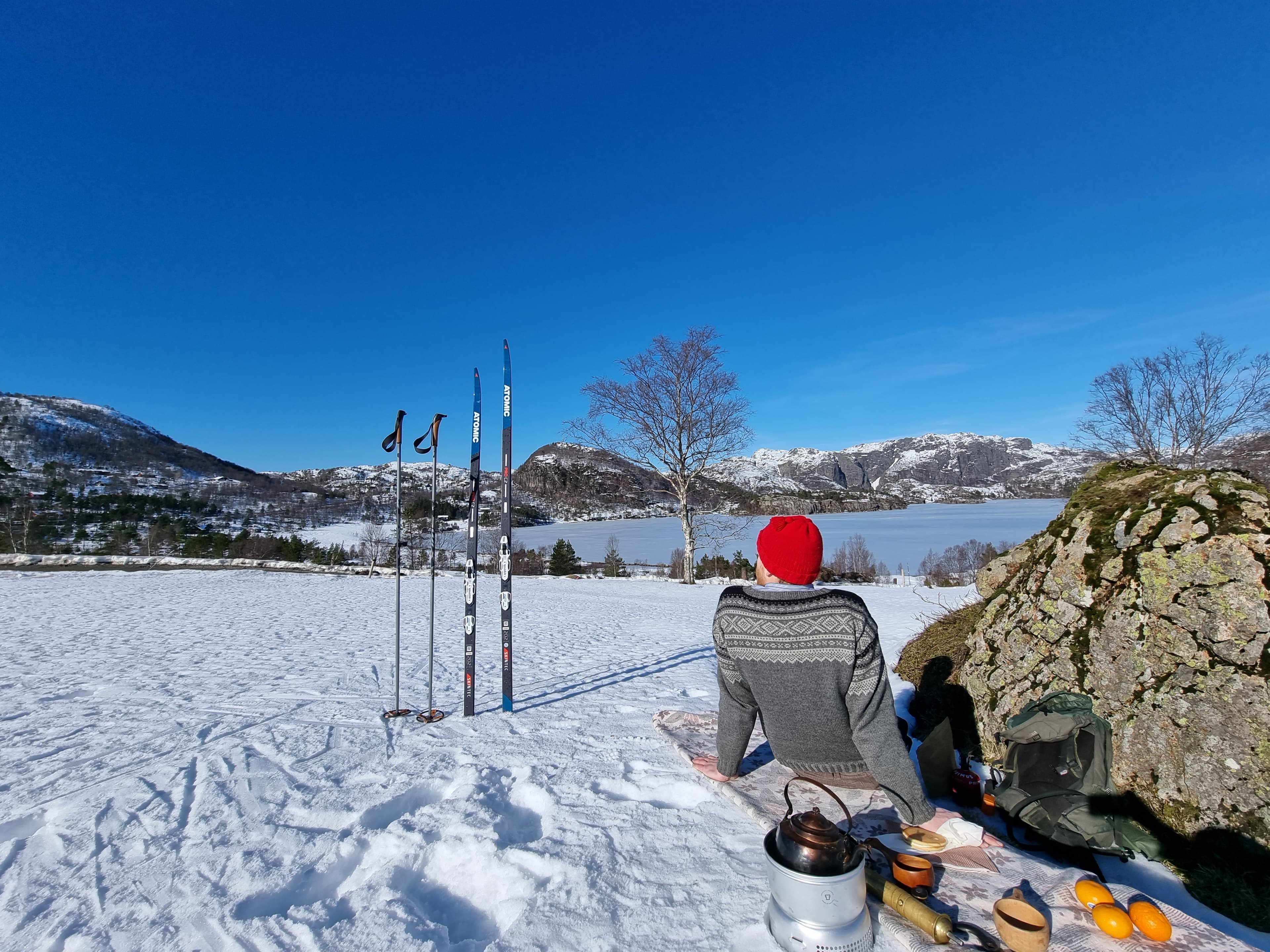 Mann som sitter og tar en pause fra skituren med kaffe og appelsiner.