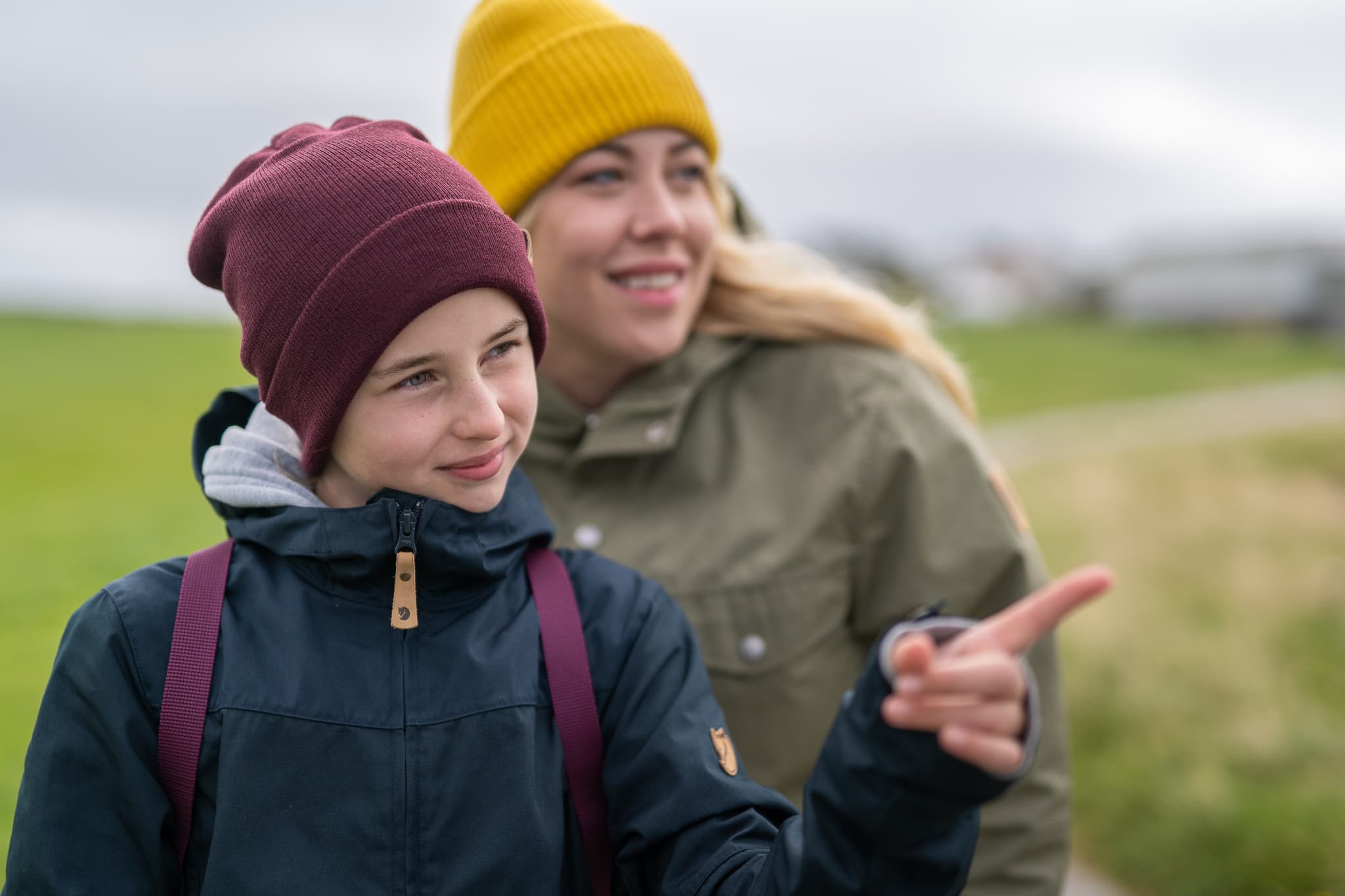 Jente og dame med turklær peker på noe i landskapet
