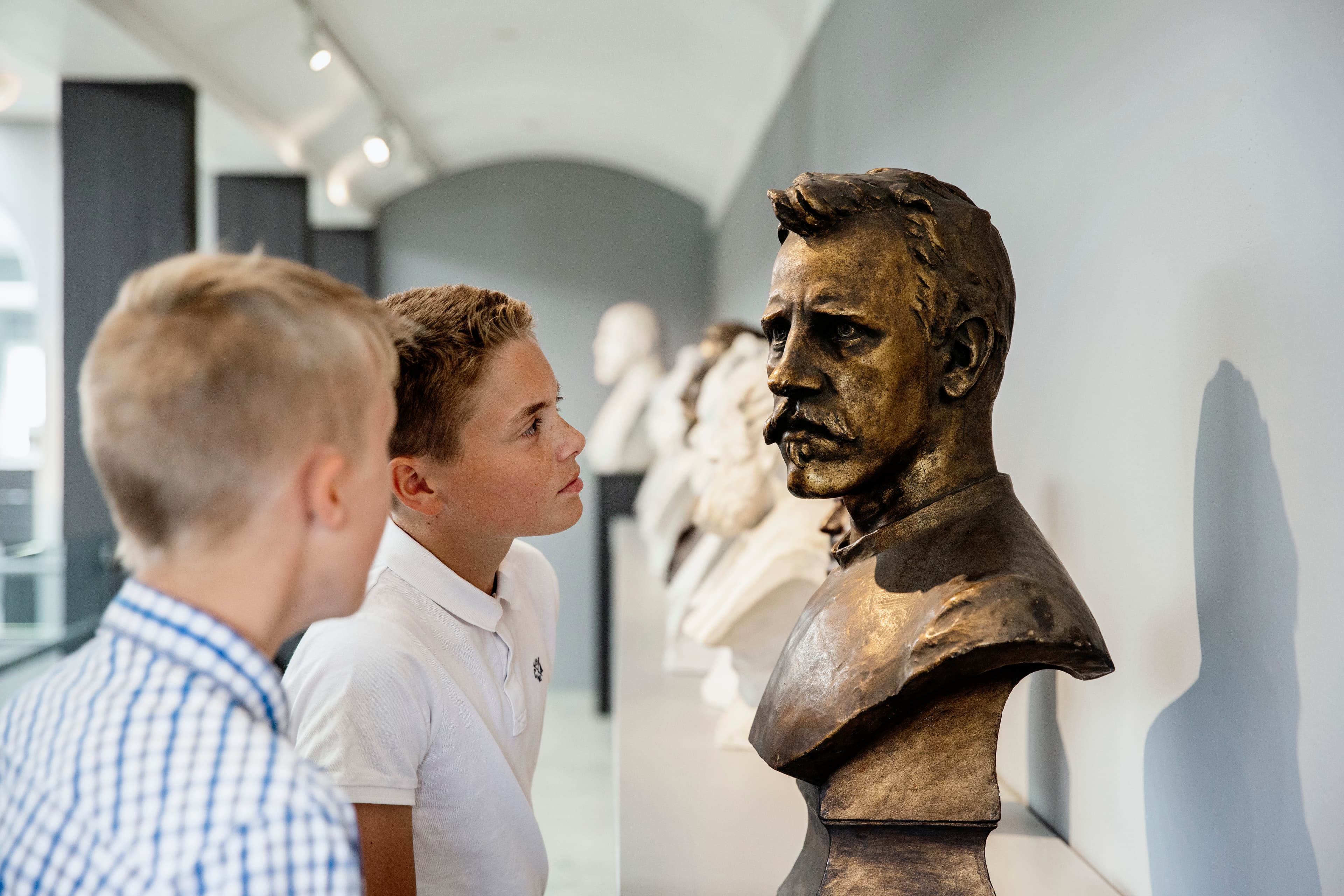 Gutar studerer ei byste av person på Anders Svor-museet.