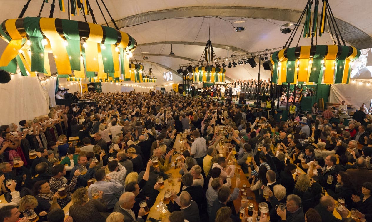 Masser av folk sitter langs langbord med øl på Oktoberfest i Egersund.