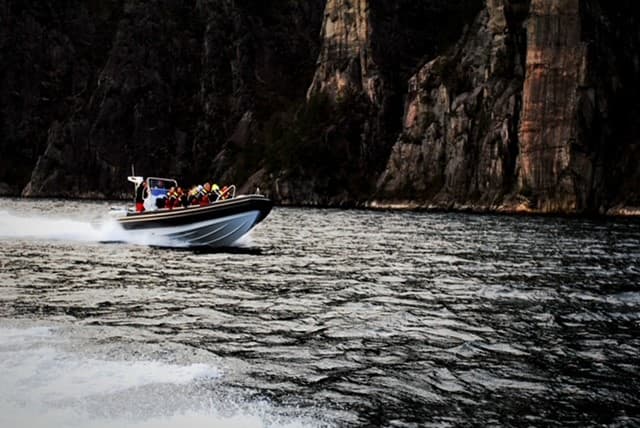 Rib-båt med mennesker ombord i Lysefjorden i fart.