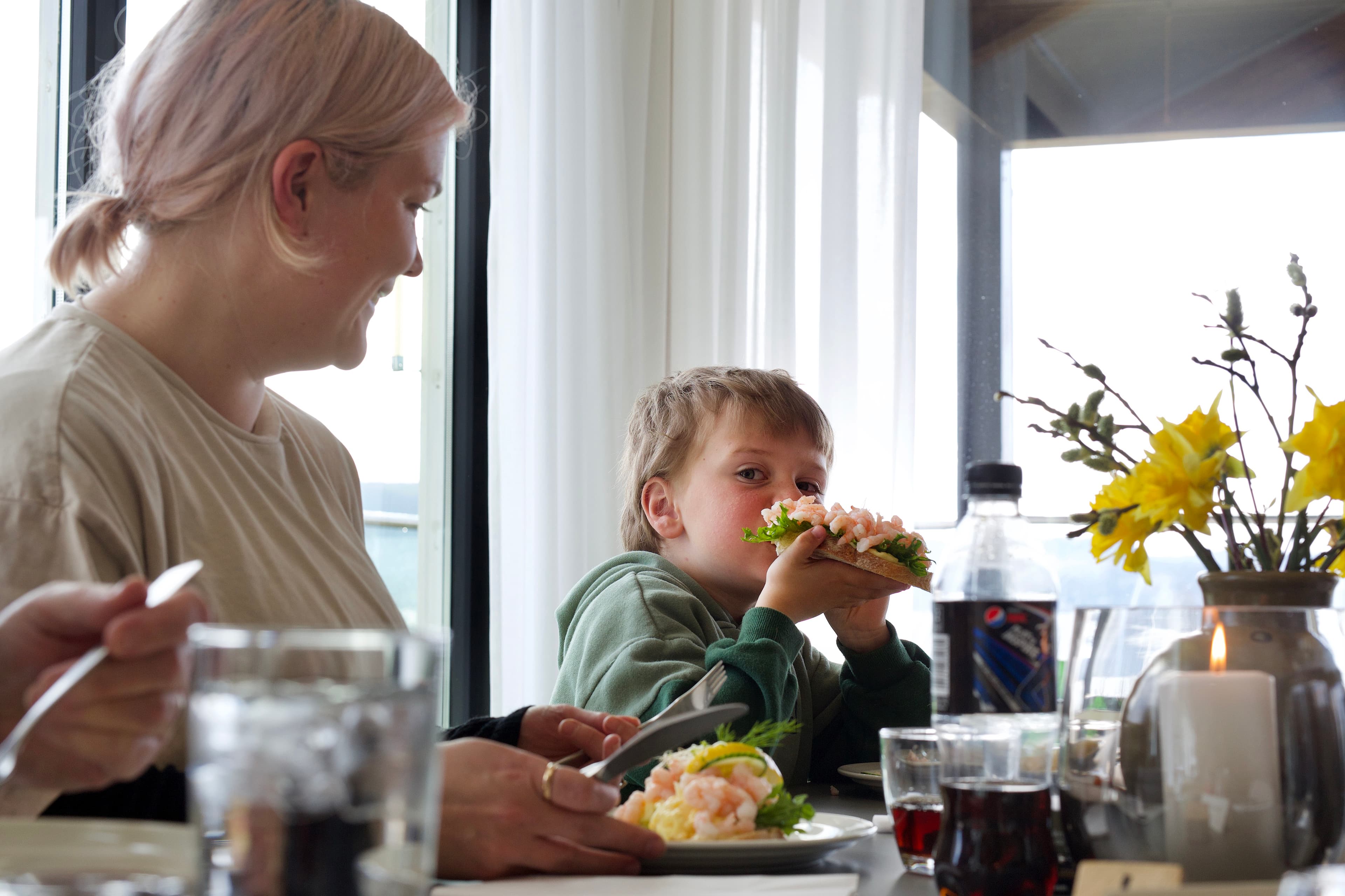 A woman and a boy eating a sandwich with scrimps.