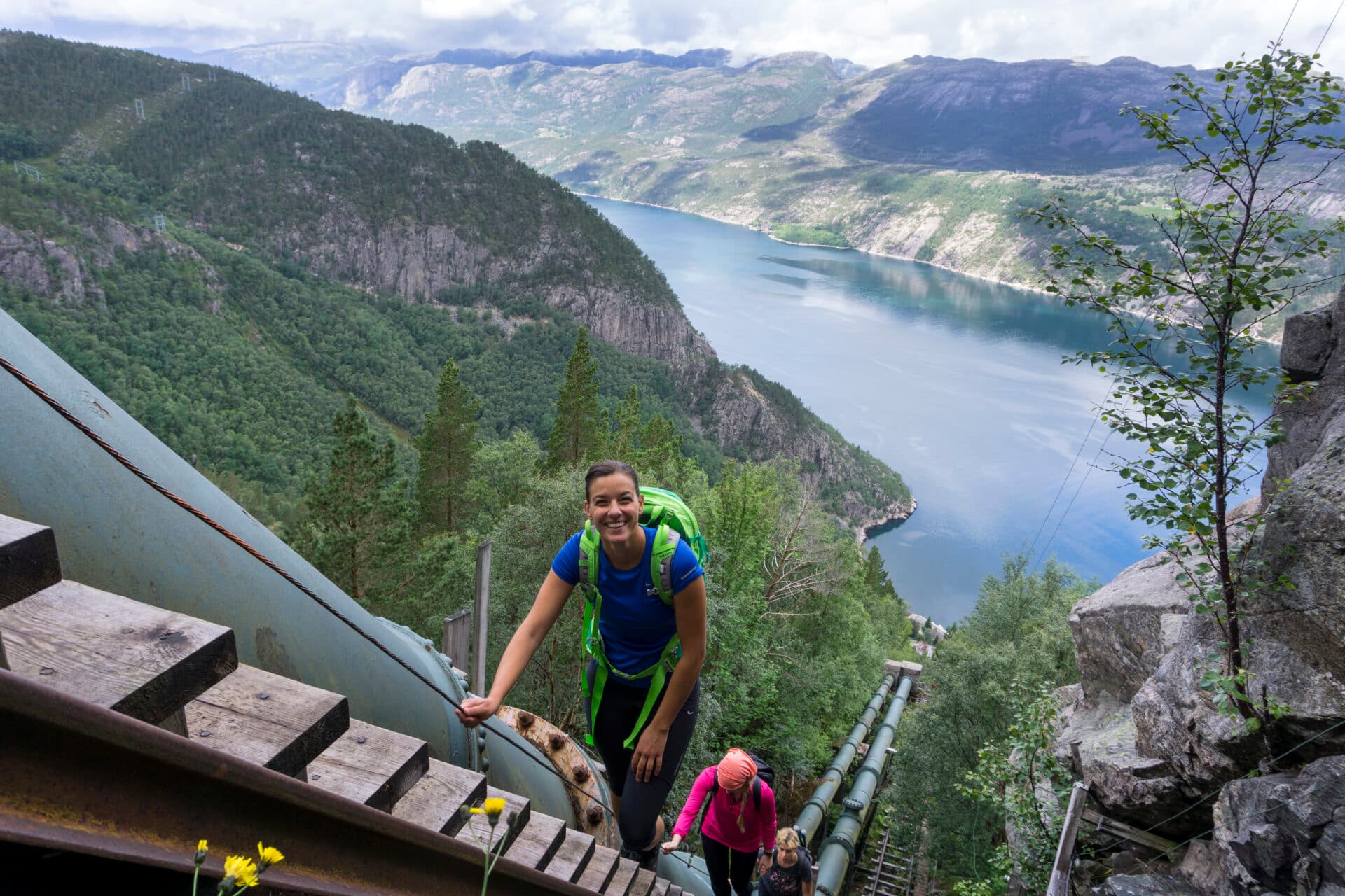 Tre personer på vei opp tretrappen i Flørli med utsikt over Lysefjorden.