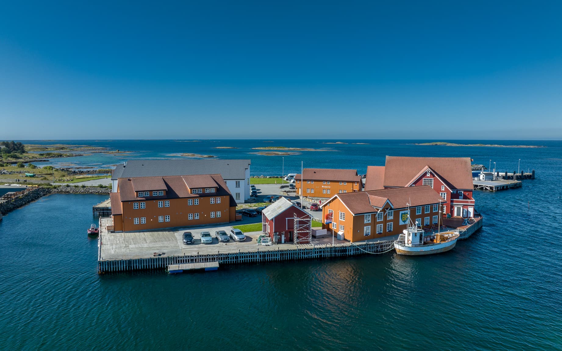 Finnøy Bryggehotell, fargerike naust og sjøbuer med storhavet i ryggen.