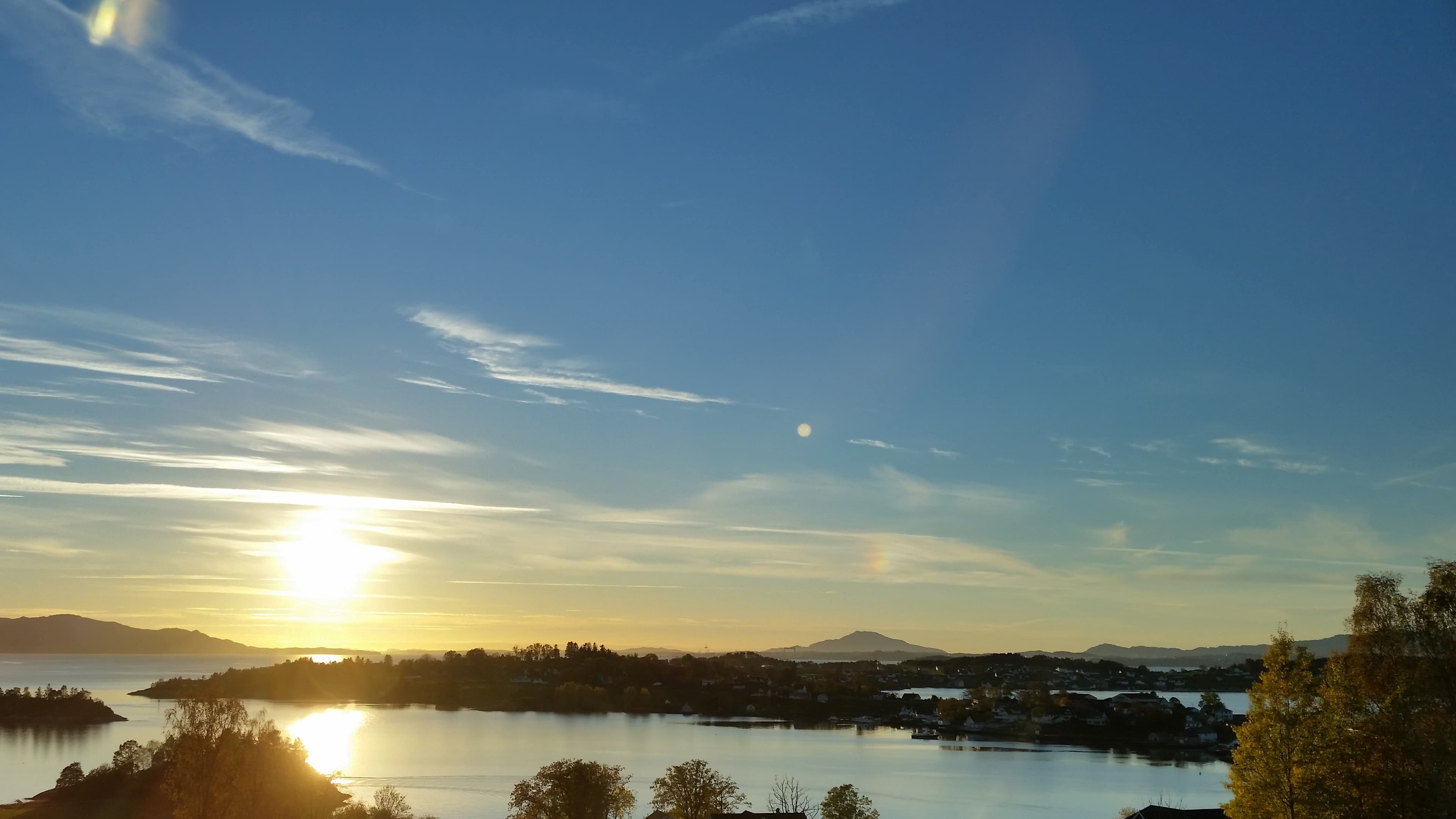 Utsikt over Halsnøy i Kvinnherad med fjellet Siggjo på Bømlo i bakgrunnen, sjø.