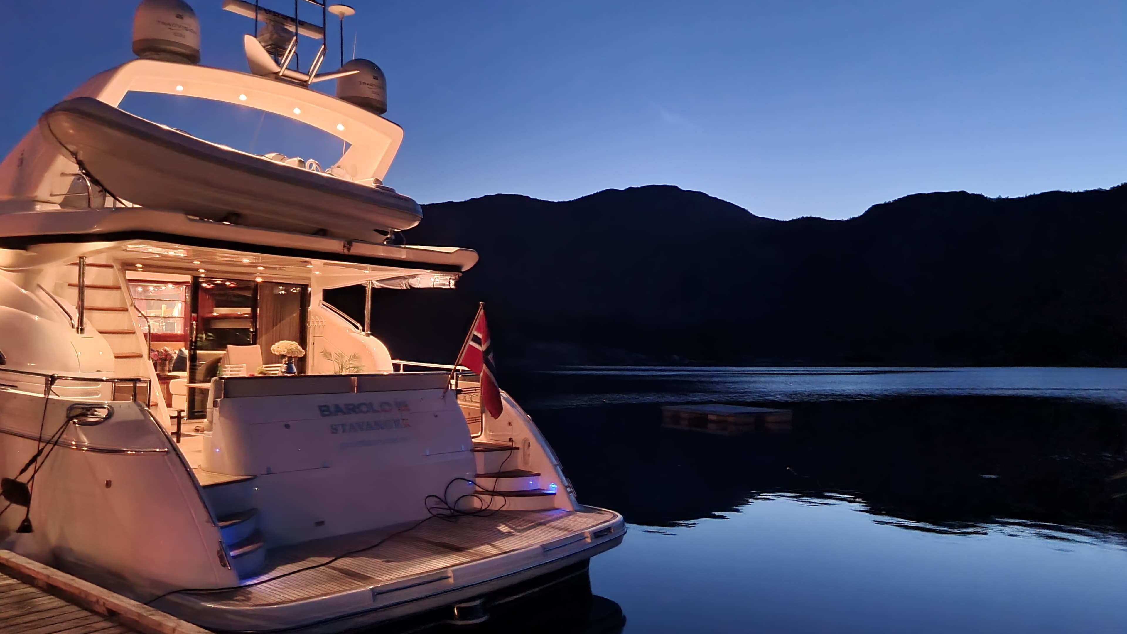 Yacht på fjorden opplyst. Fjeller i bakgrunn.