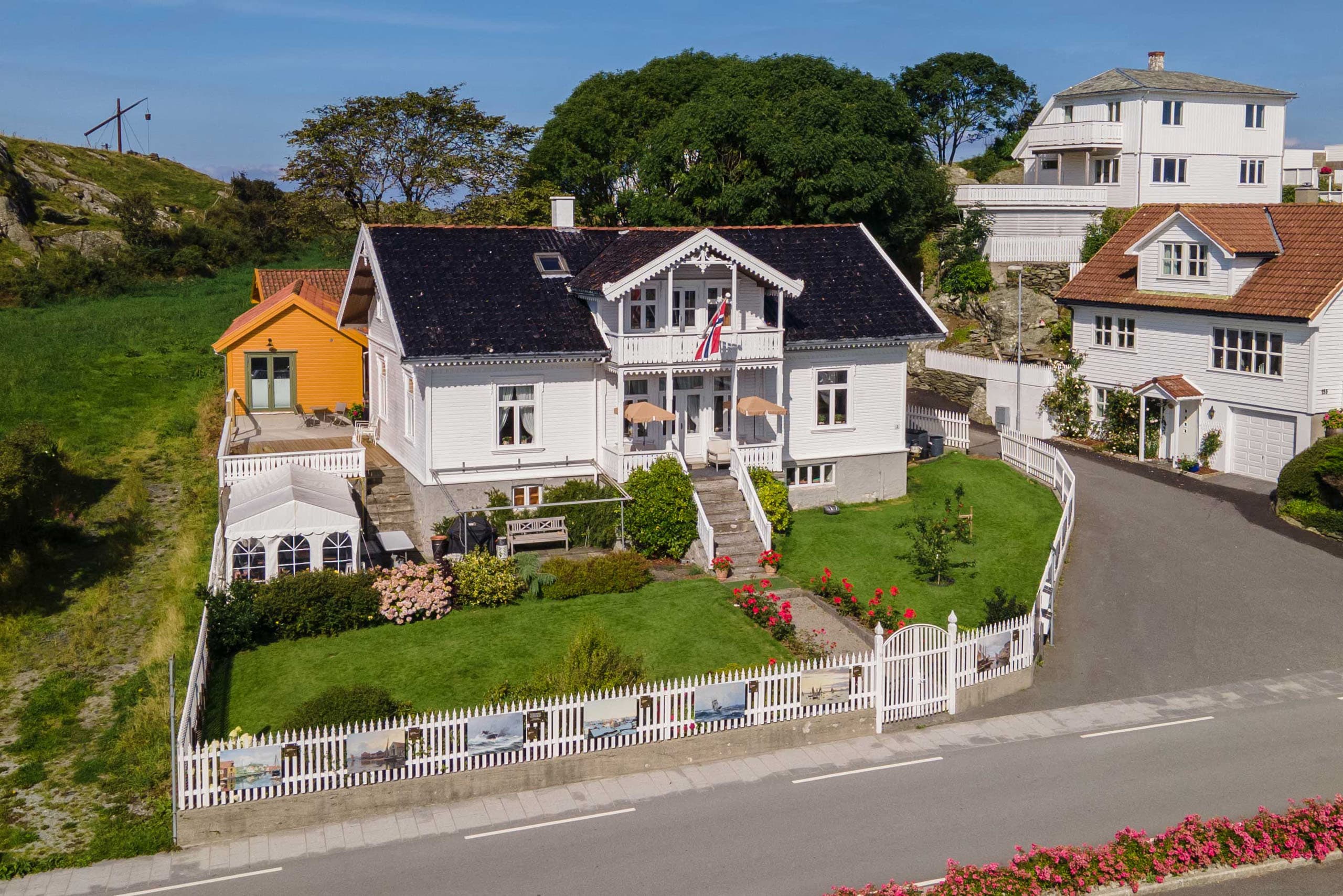 Et hvitt Sveitserhus på Kvitsøy med en grønn, inngjerdet hage.