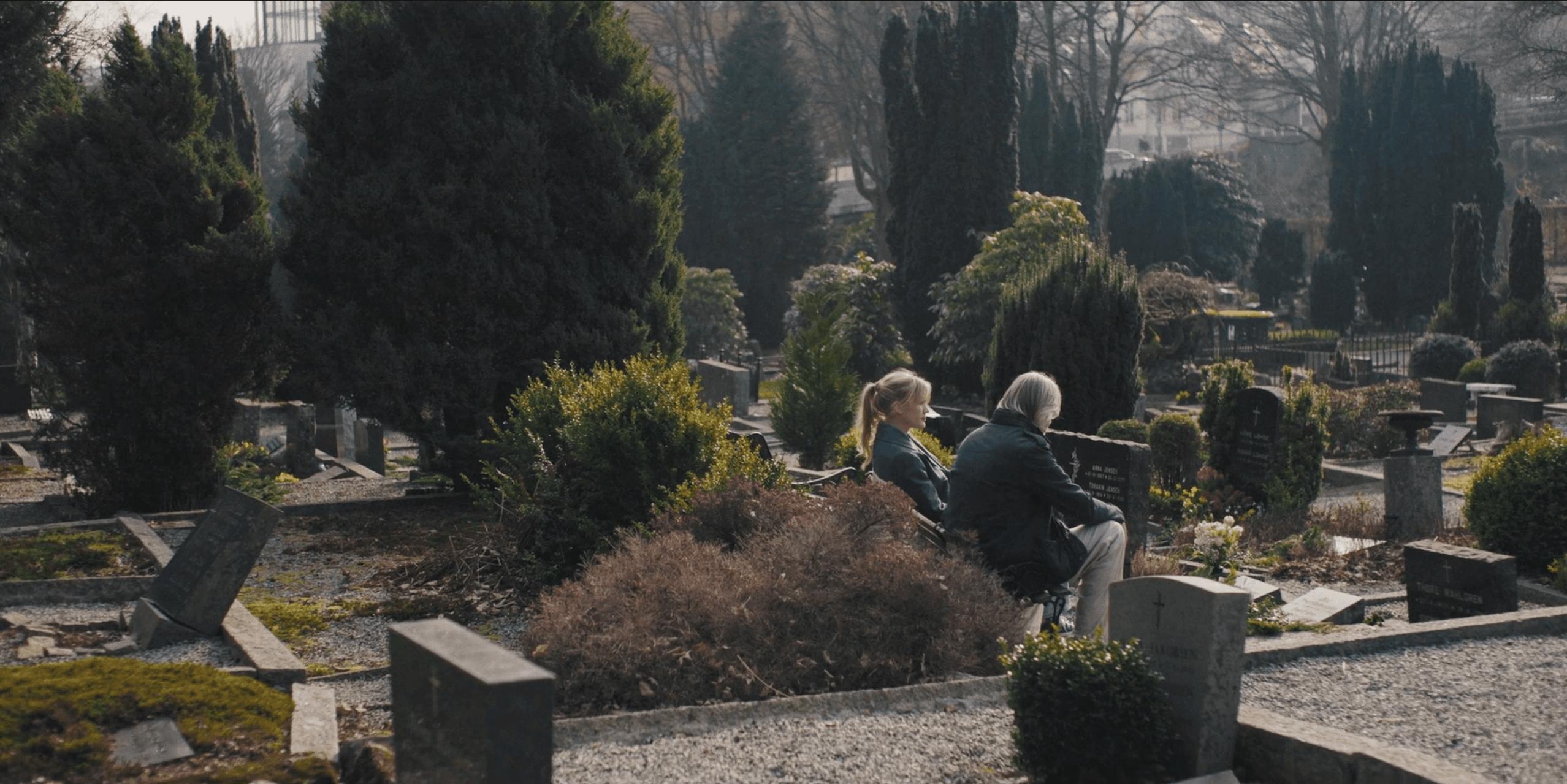 far og datter sitter ved grava