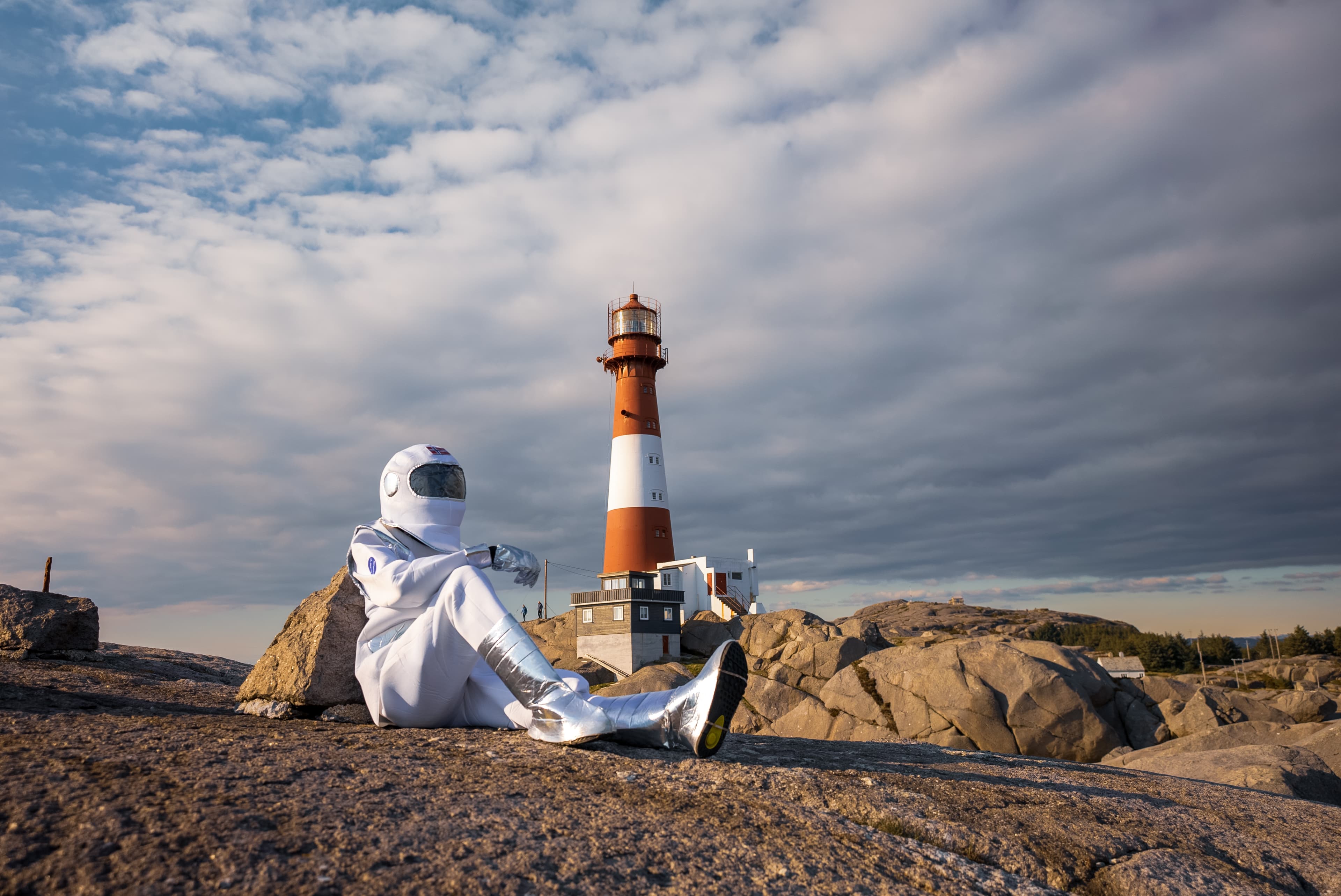 Mann i månedrakt sitter på berget ved Eigerøy fyr