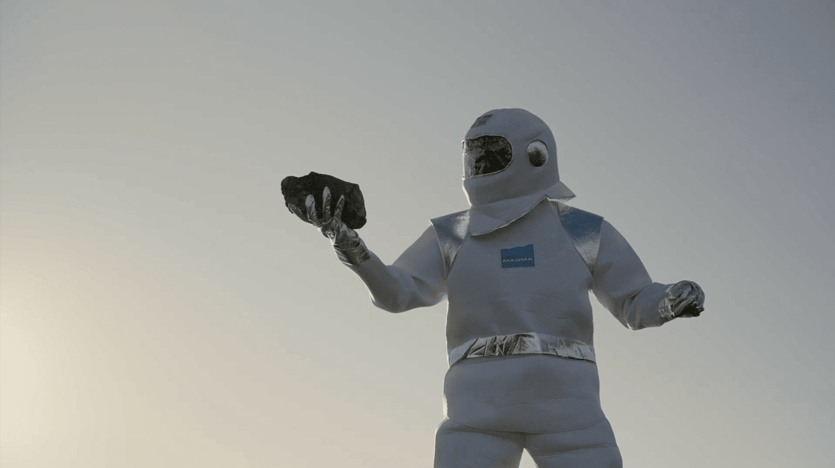 Mann i månedrakt holder anortosittstein i hånden.