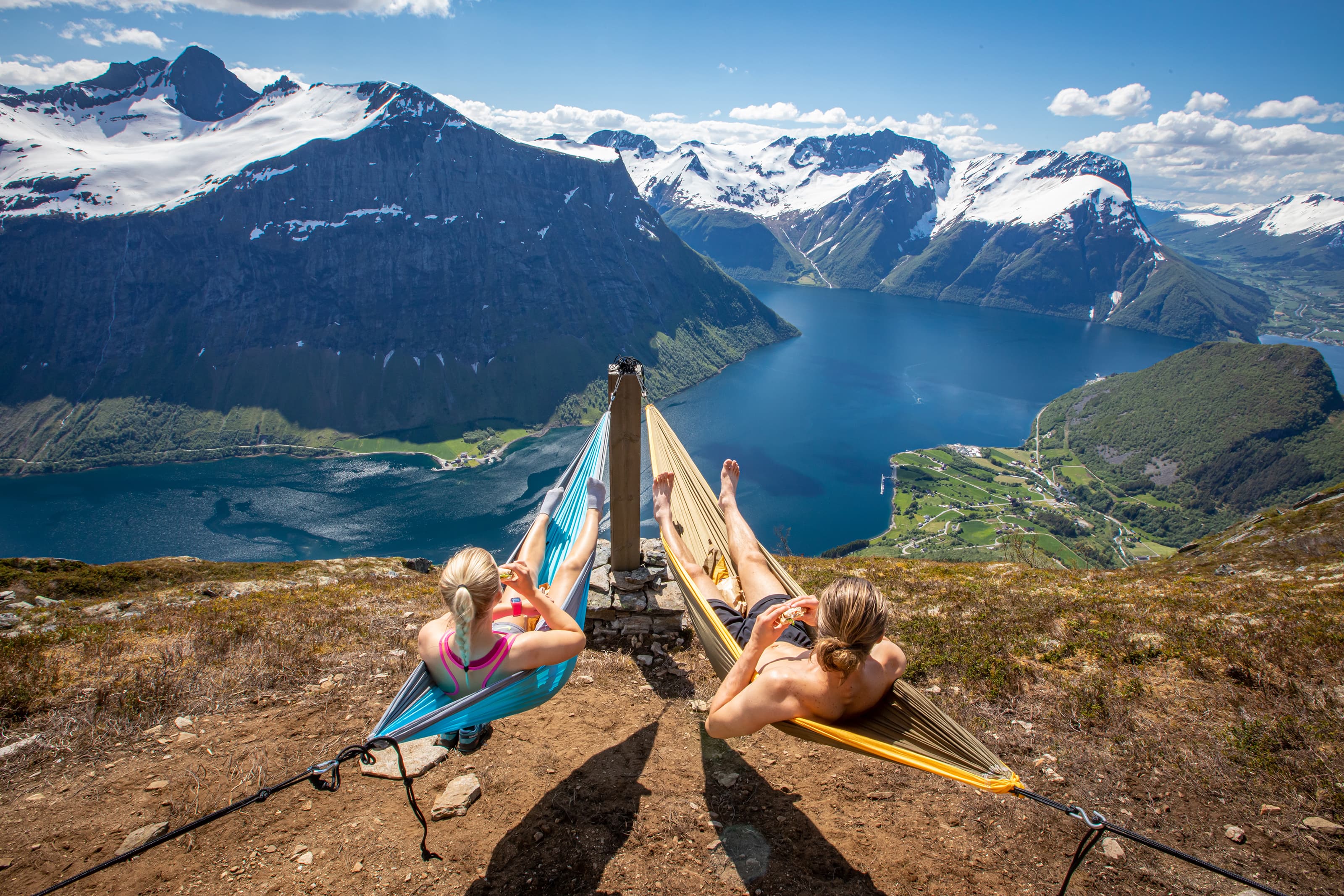 to personer i hengekøye på toppen av Egilbu med utsikt over Hjørundfjorden.