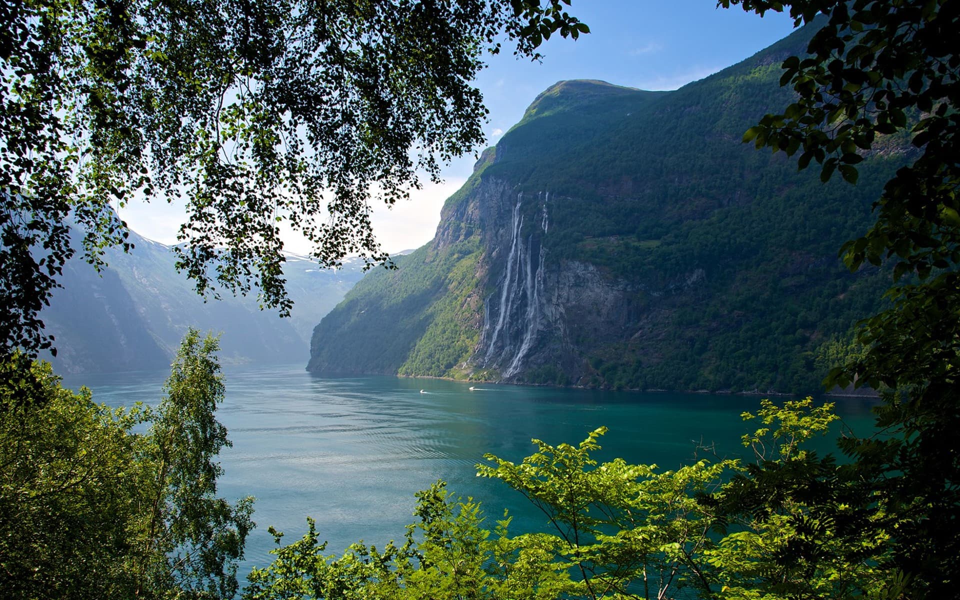 Geirangerfjorden omkranset av fjell og grønne trær.