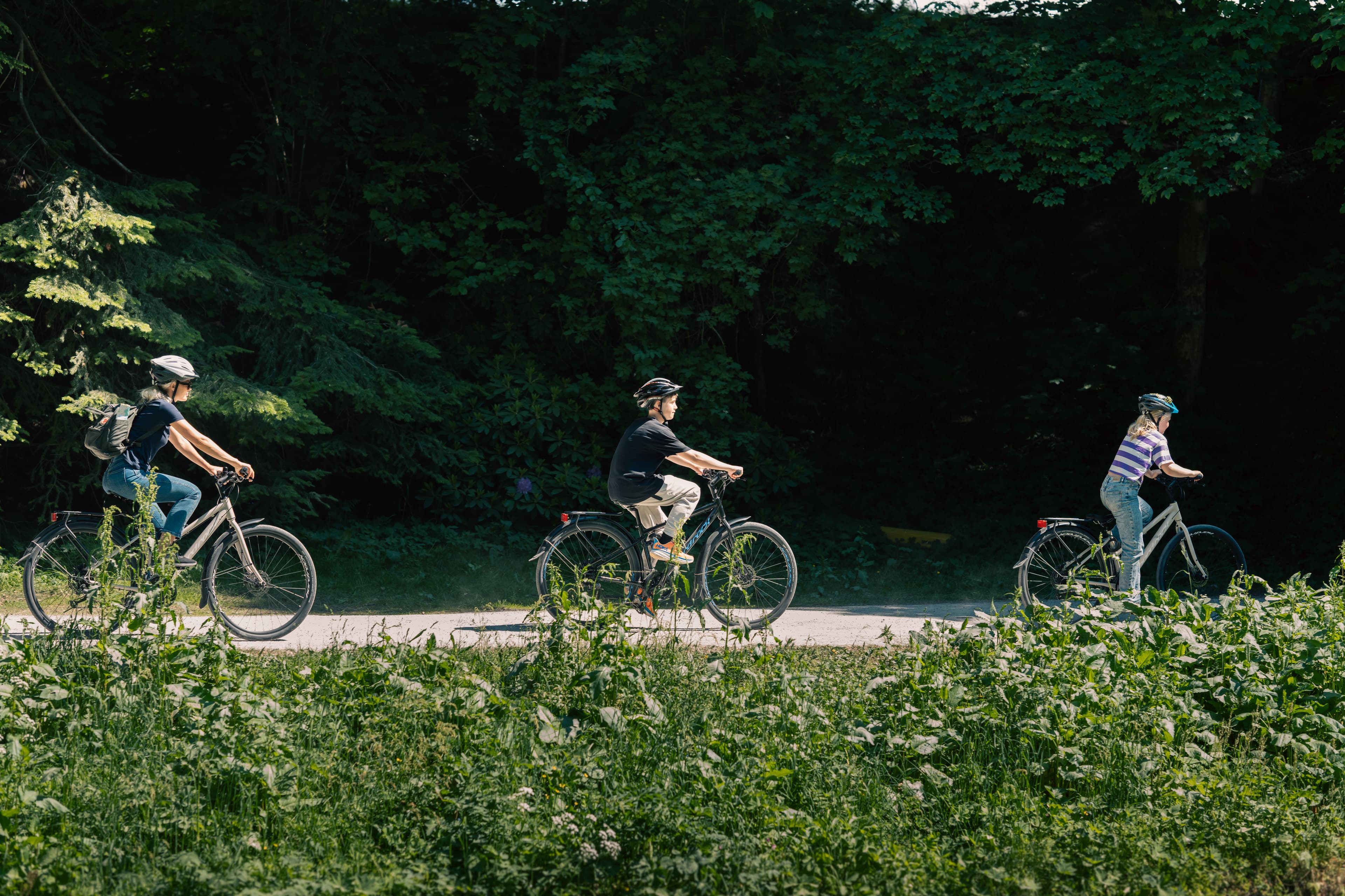 En mor med to barn sykler på en grusvei