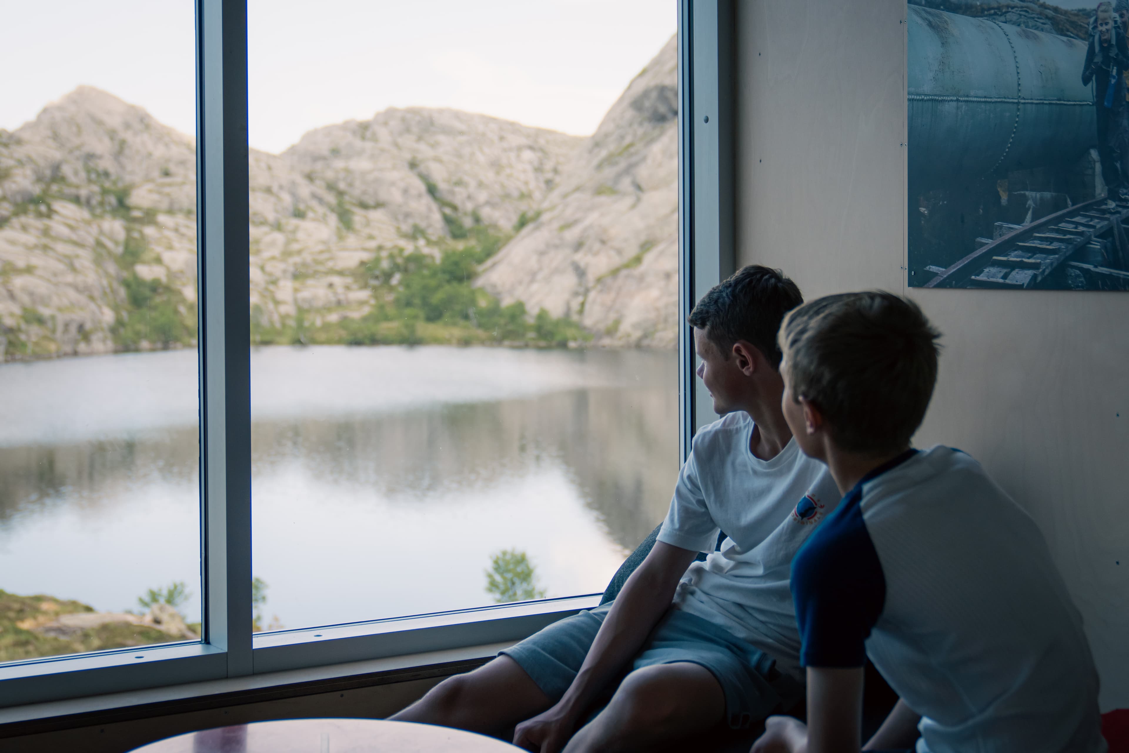 To gutter som kikker på naturen gjennom et hyttevindu