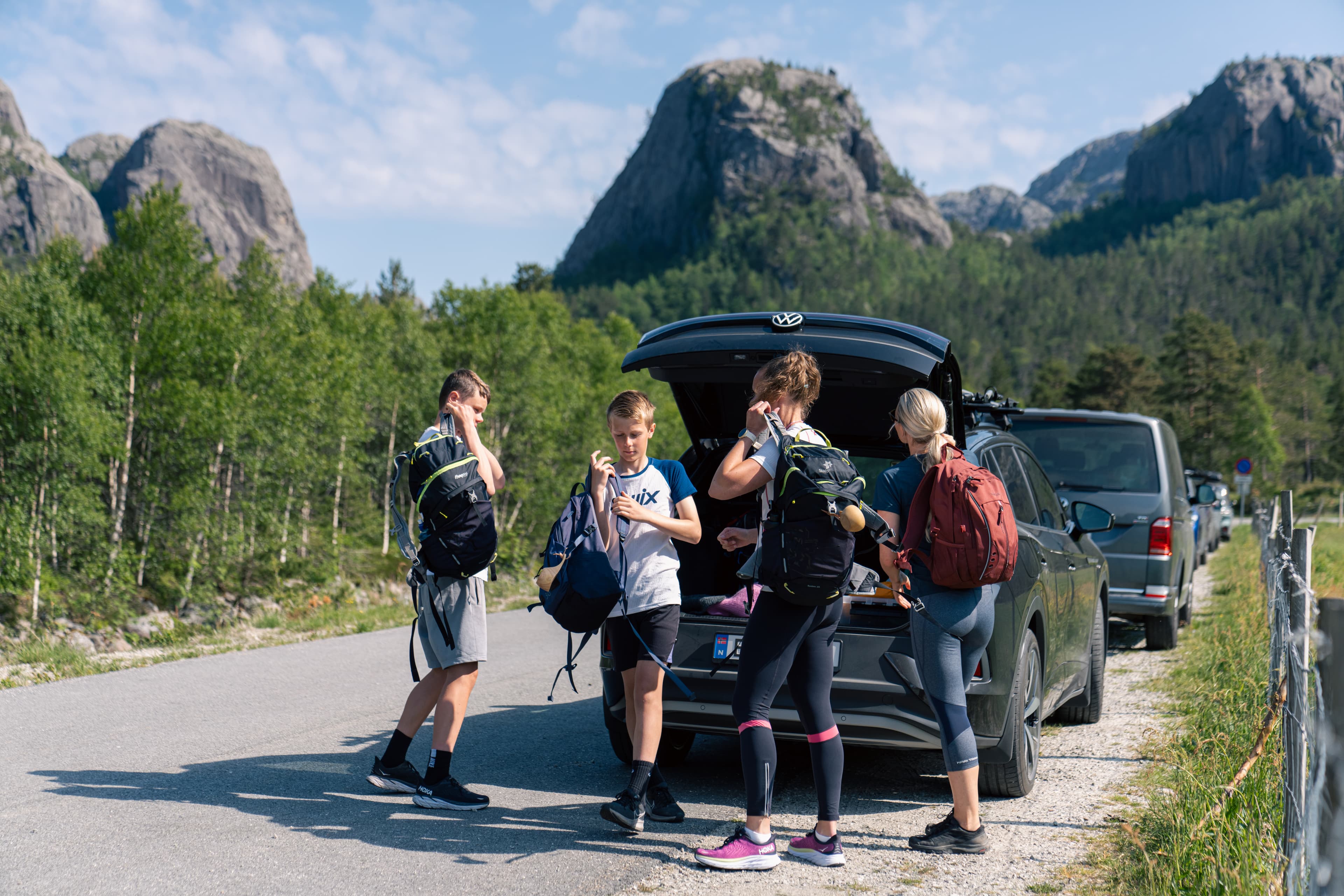 En familie som pakker tursekkene ut av bilen i et fjellandskap