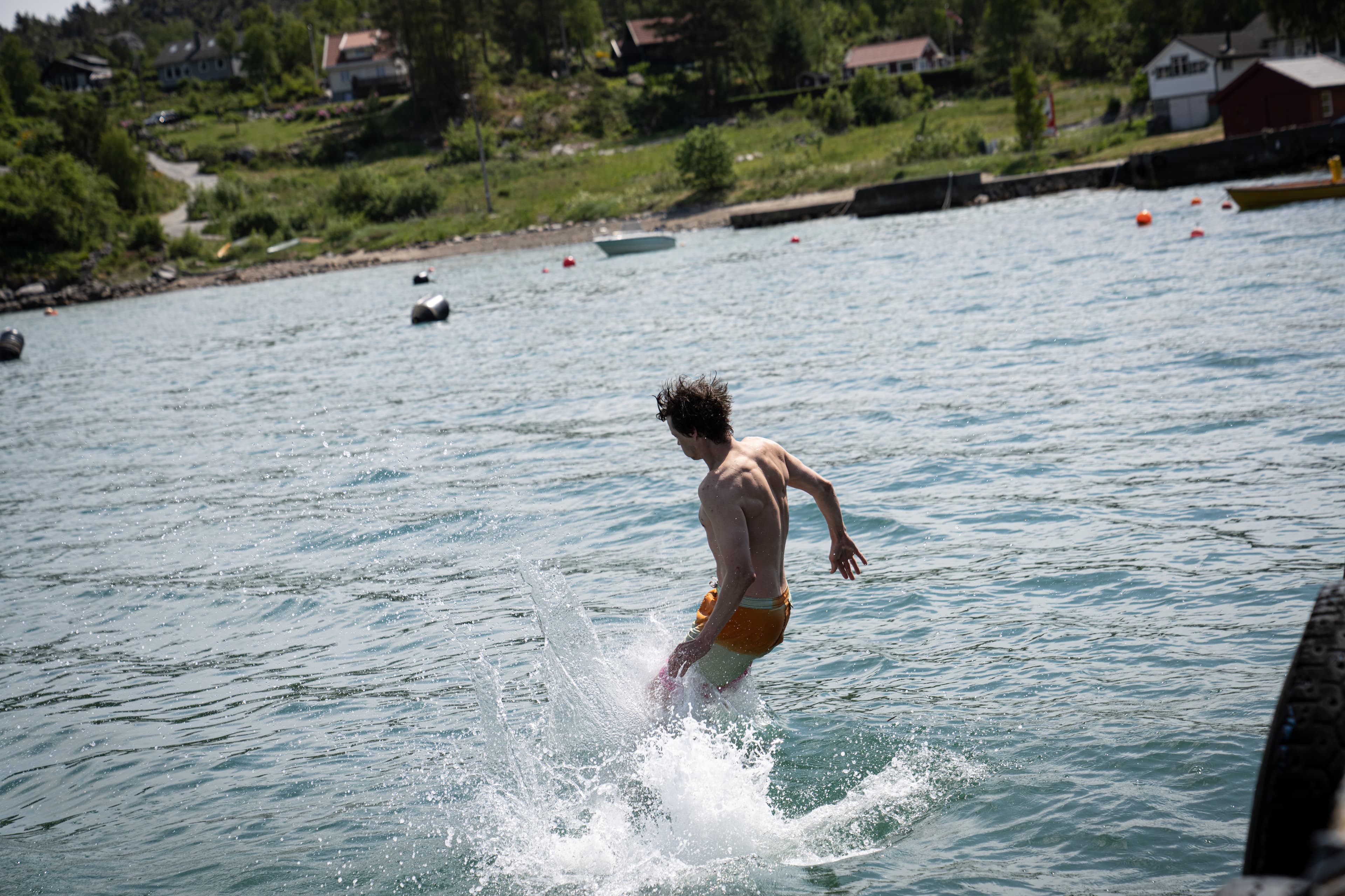 En gutt hopper i vannet med beina først