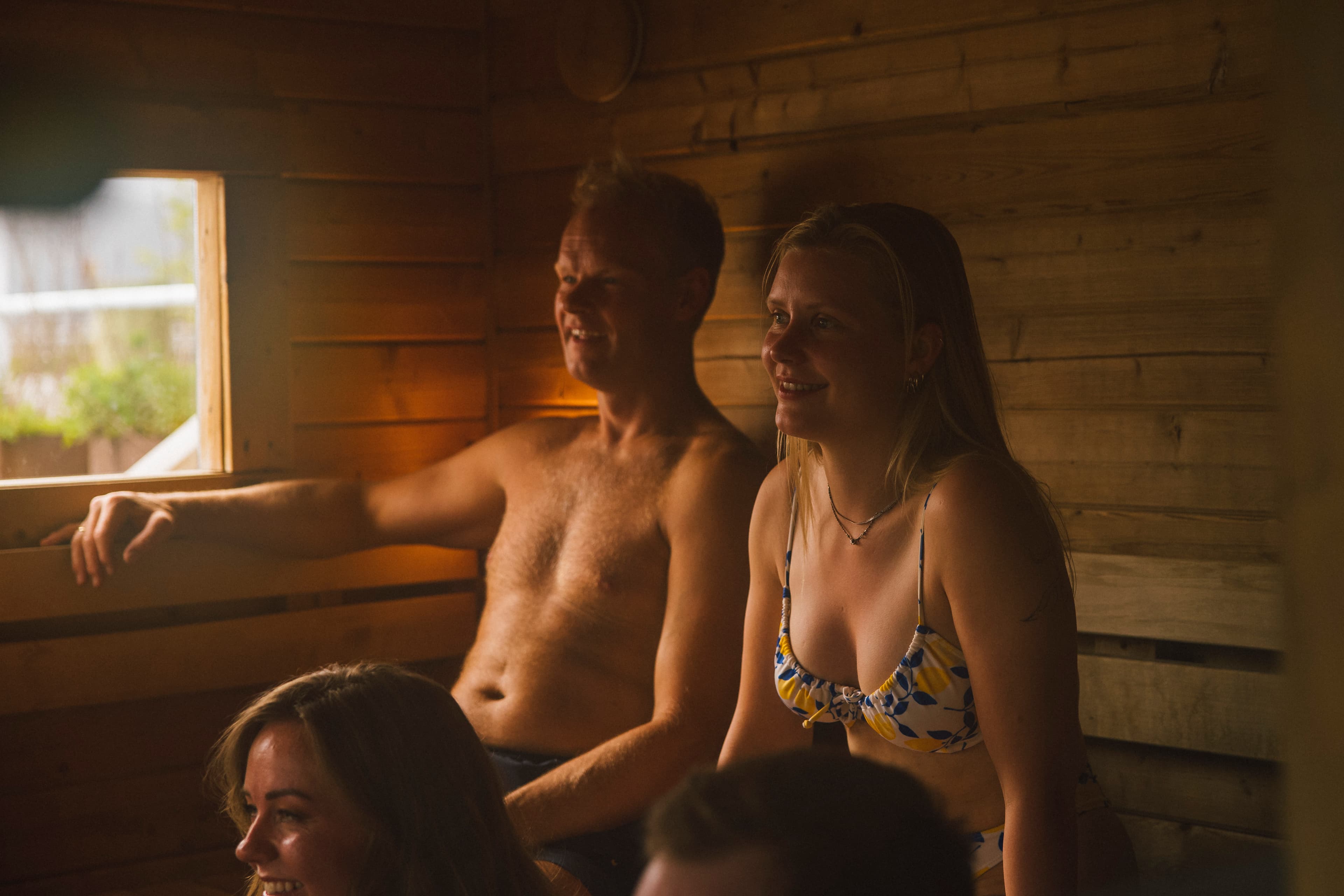 Four people inside a sauna talking and laughing.