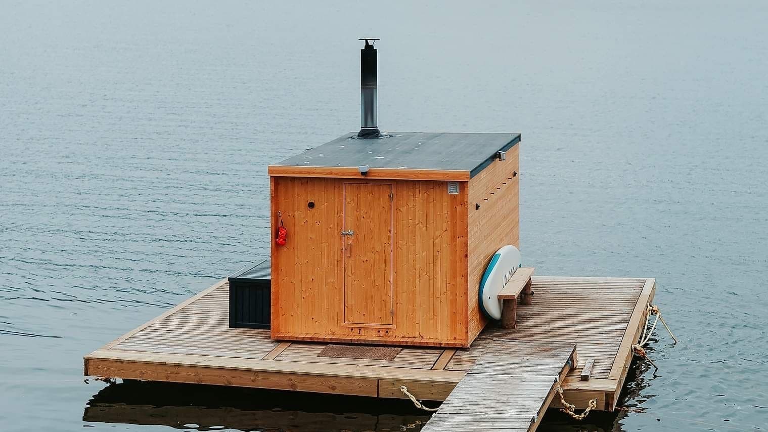 Sauna flyter på vannet. Fjellandskap bak i det fjerne