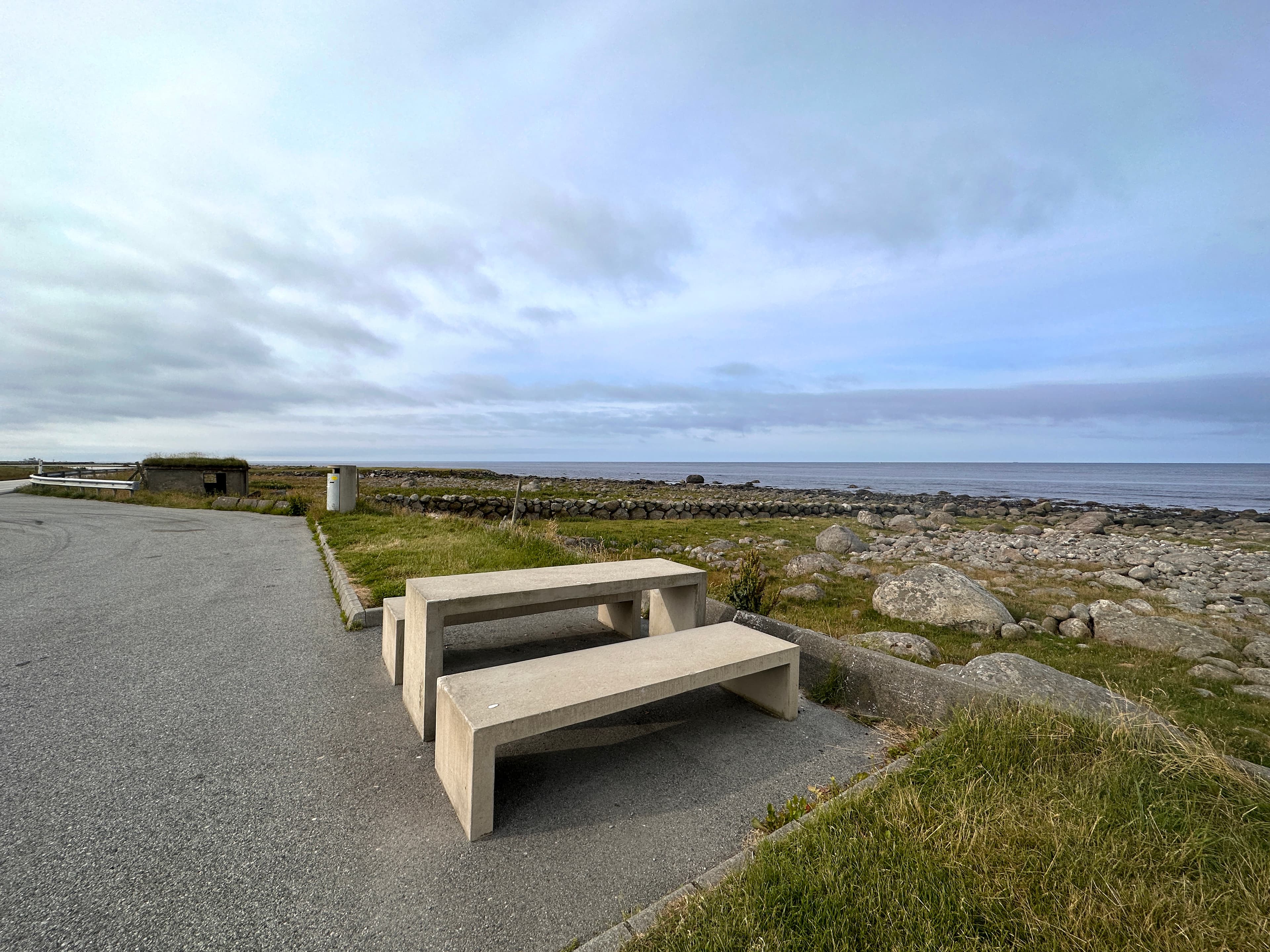 A rest area with picnic table and benches with a sea view.