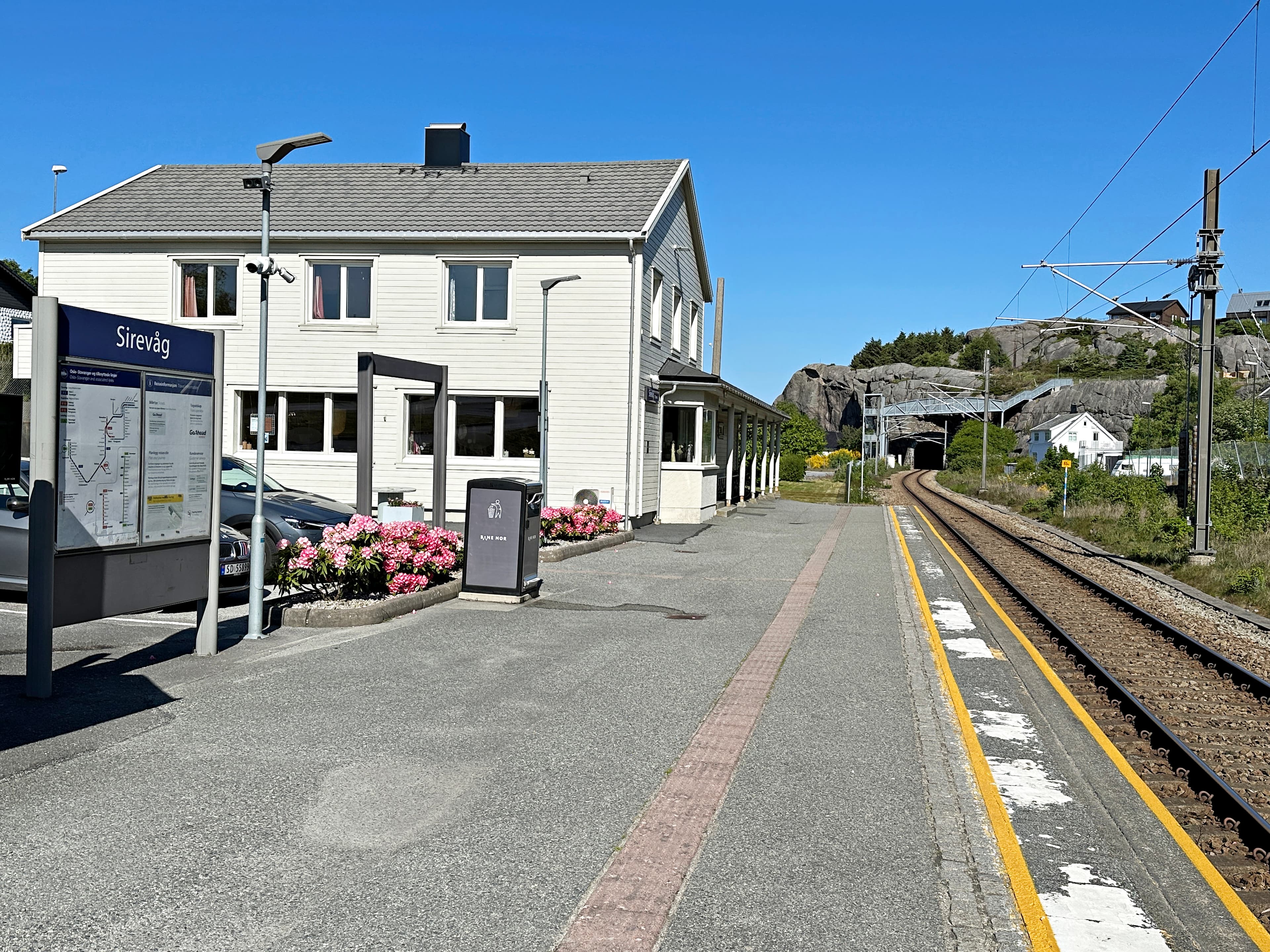 Sirevåg train station - a small white station house, the rails and a mountain