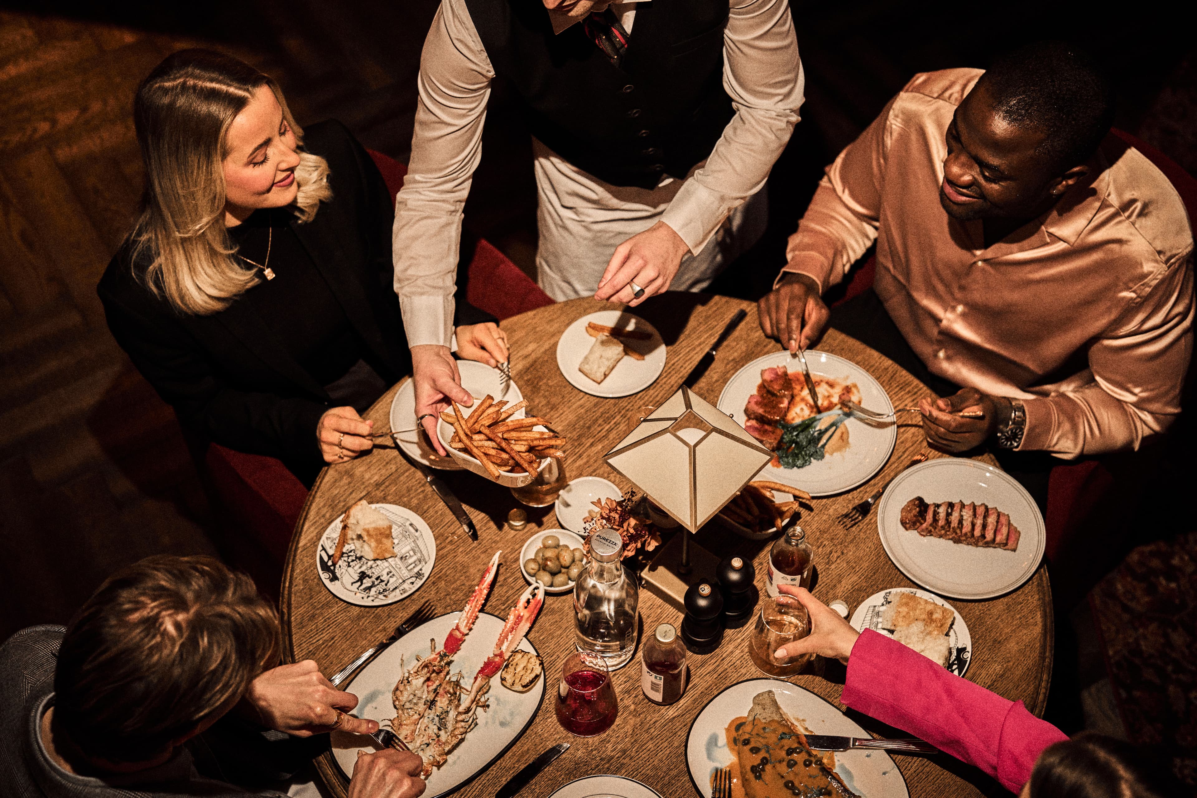 People seated at a restaurant table where the dishes are served by the staff at the Brasserie Pigalle in Stavanger, Norway.