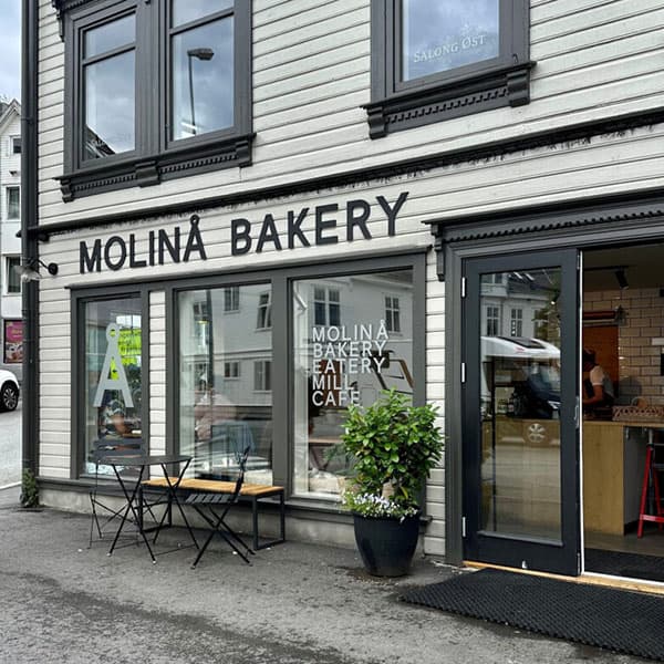 facade of a bakery in white and green. A wooden house.