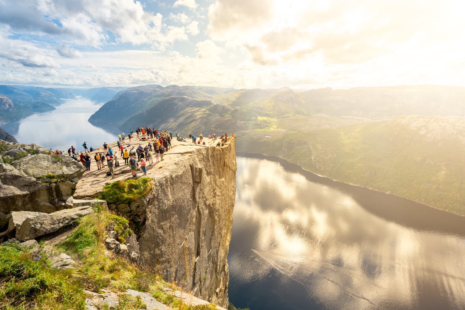 Preikestolen mountain plateau with people on top and the blue fjord below.