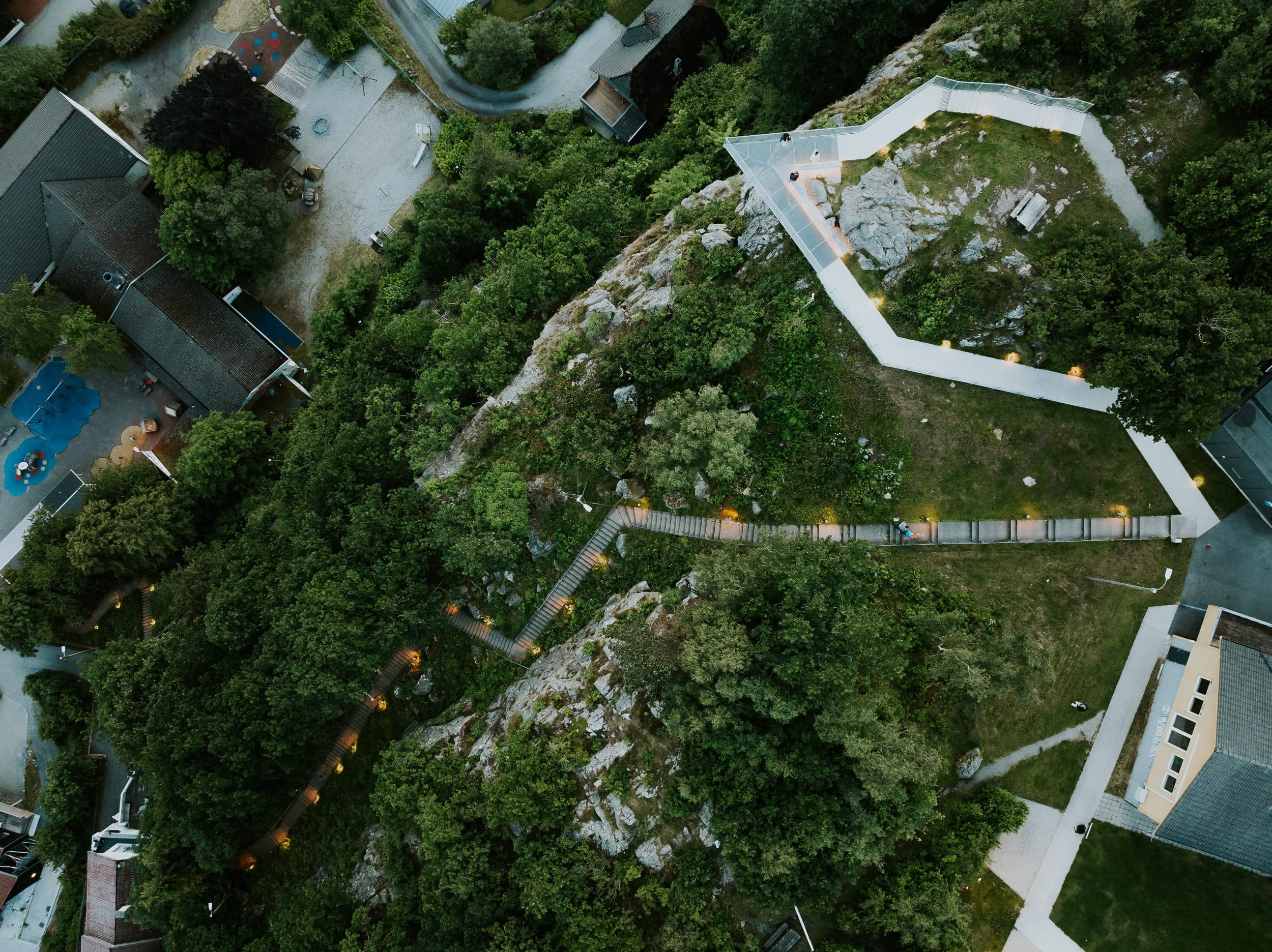 Two people and a dog walking up the stairs to the mountain Hanafjellet. The stairs are called Hanatrappene. From the top the view shows Sandnes and fjord