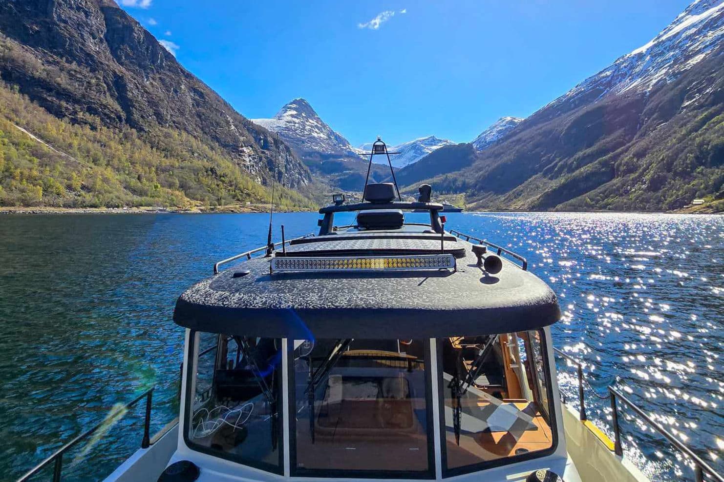 Båten ligger fint i Geirangerfjorden med Geiranger i bakgrunnen.