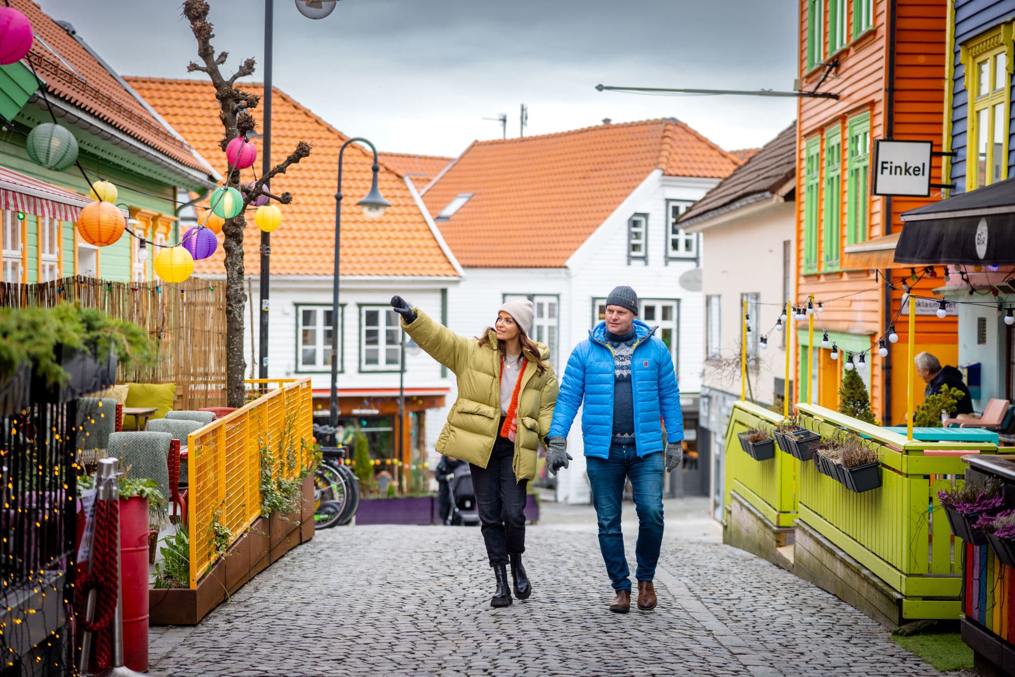 Fargegaten Stavanger - a man and woman strolling and visiting shops and cafes in the street of colours in stavanger. They look at street art and houses.