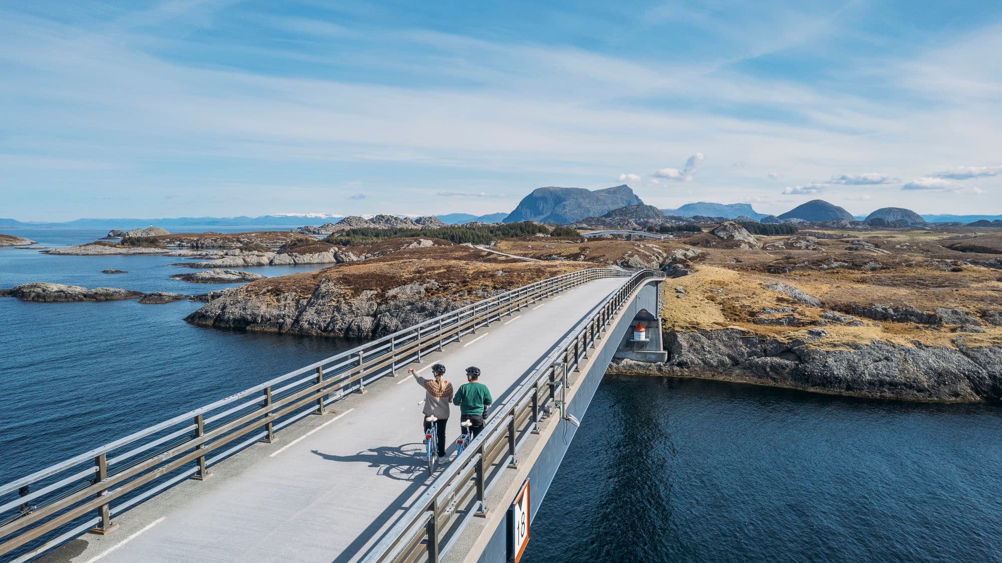 to personer står på brua og ser utover havet. jenta peiker