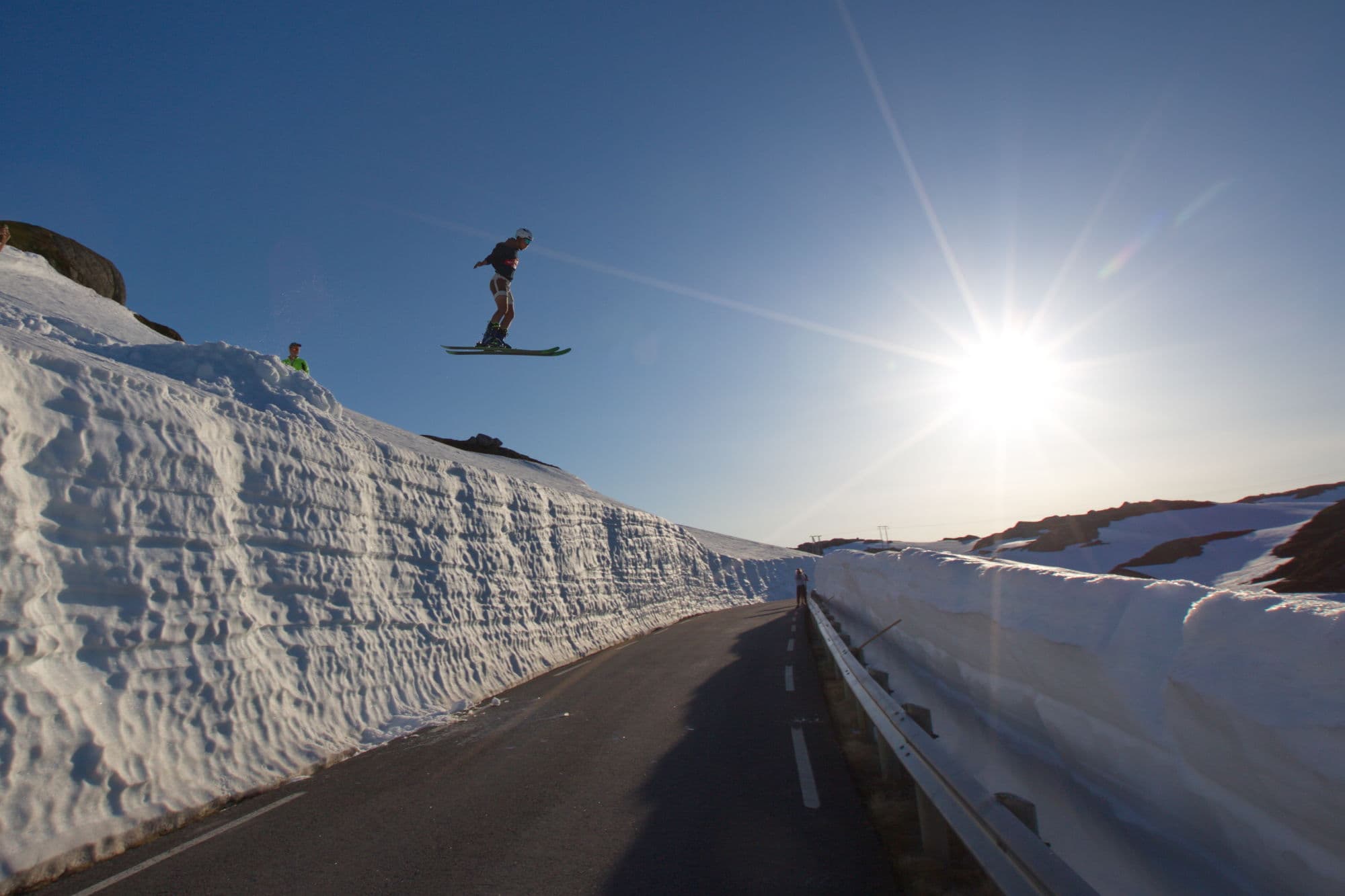 Man on skis jumps from one side of the road to the other from verge to verge