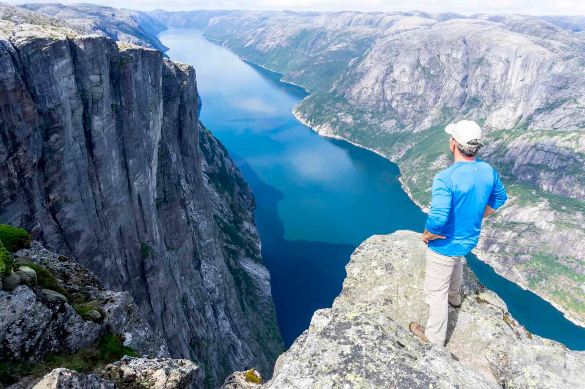 Man standing on top of mountain with fjord views