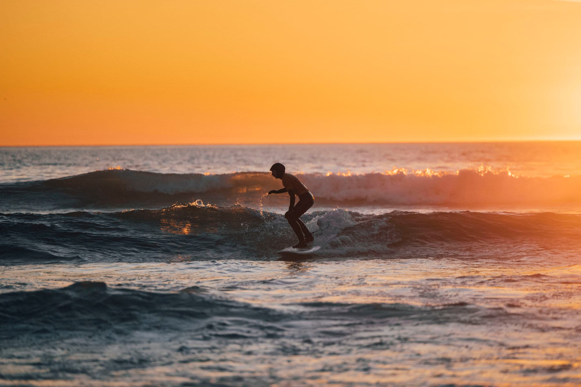 Surfer at Bore beach during sun set
