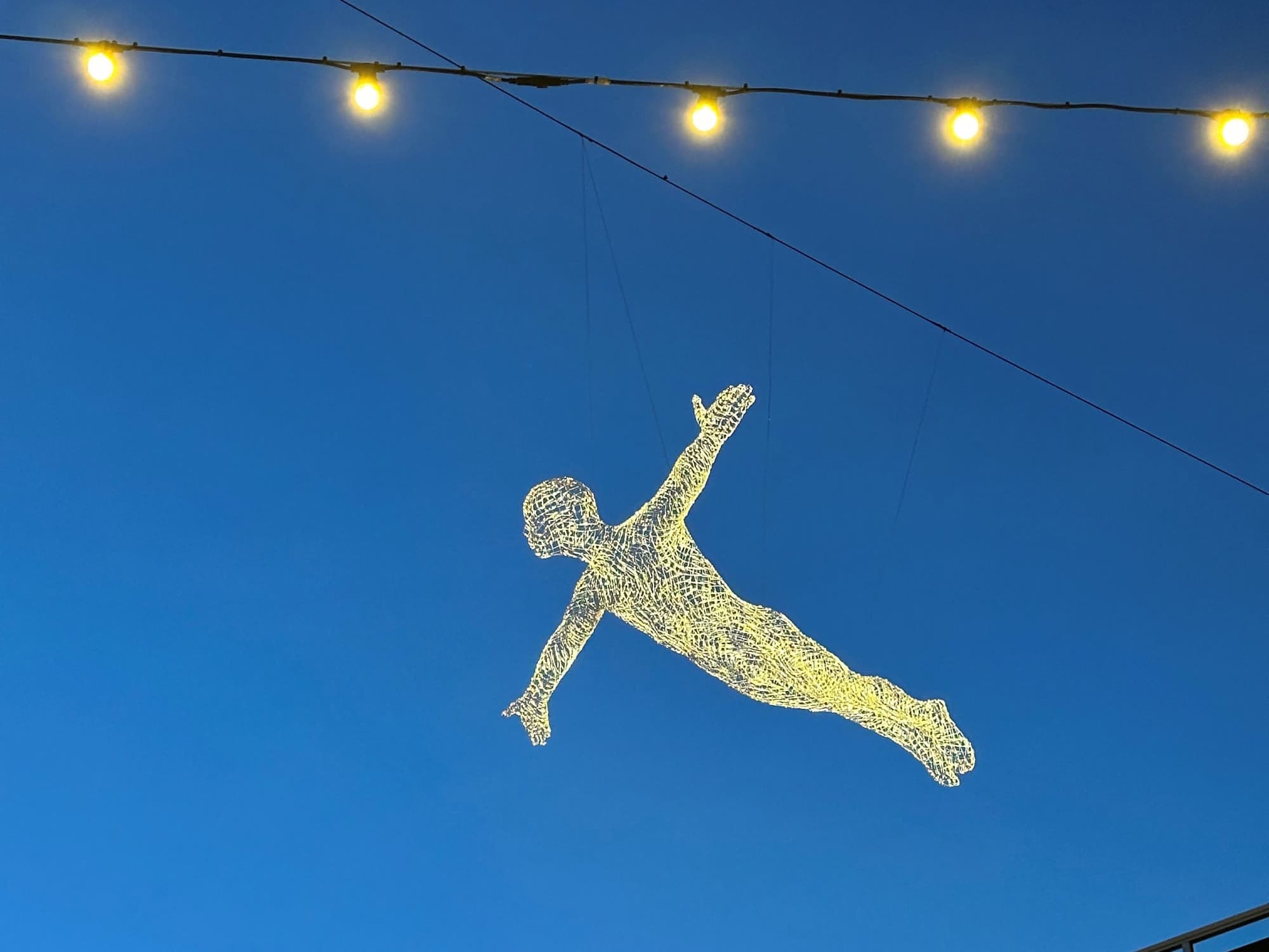 Light art suspended in the air above buildings and street in Stavanger called The Travellers