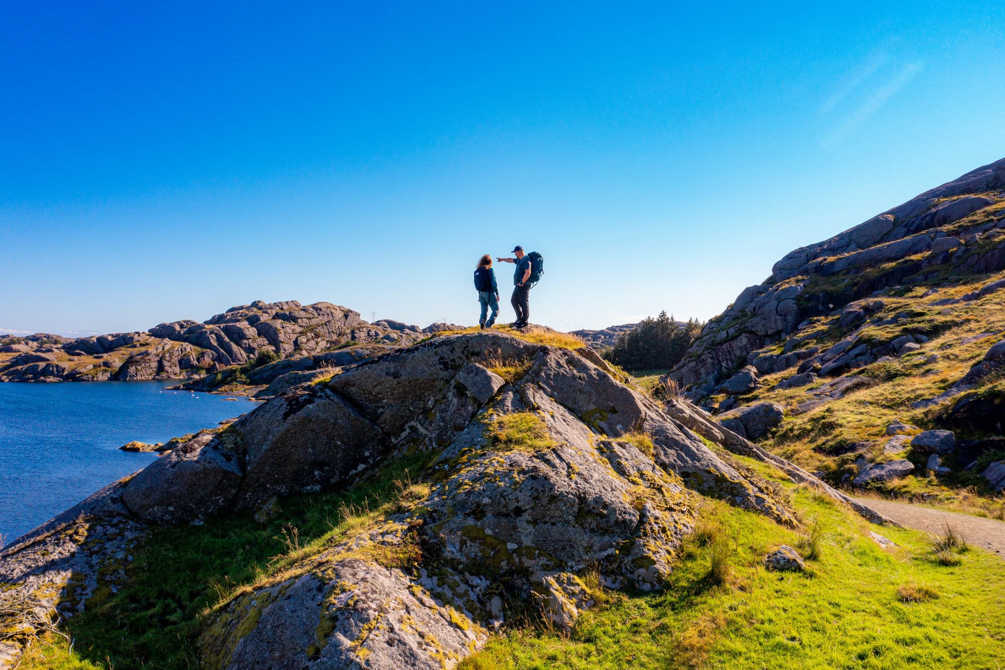 Rocky shores and mountain terrain with two people hiking.