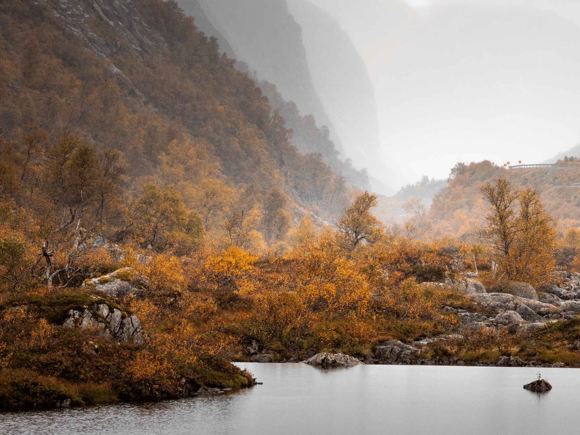 lake, vegetation in autumn colours and large towering mountainsides in the back