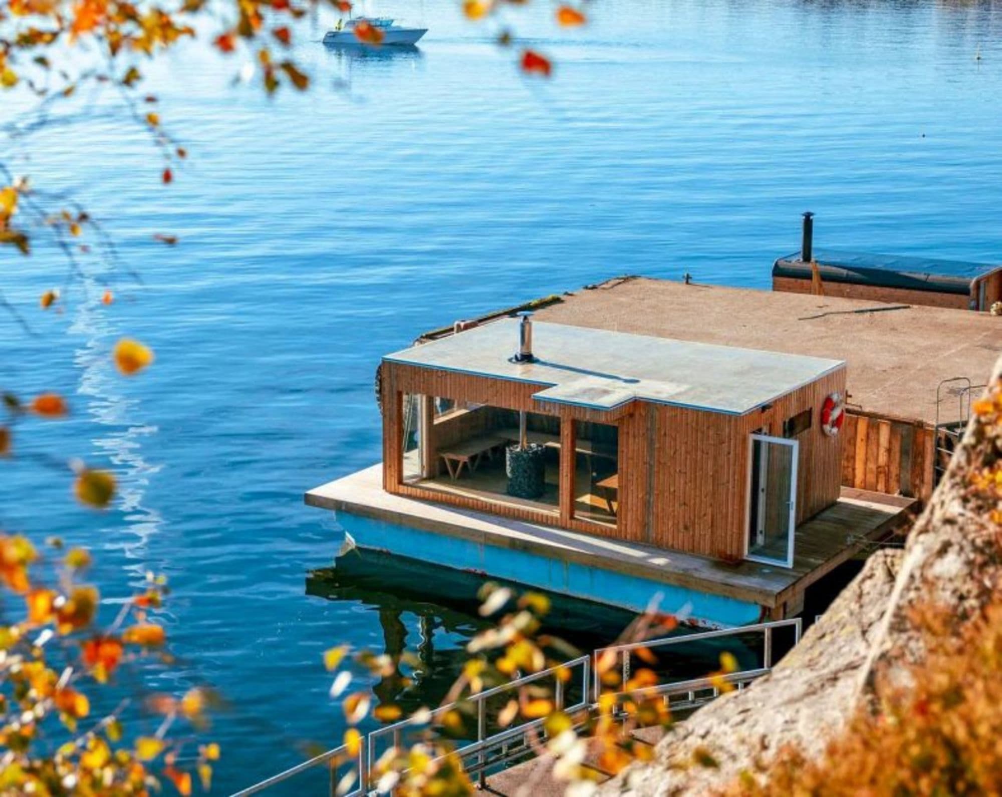 sauna on a floating deck seen from above the water is shiny and blue, reflected from a blue sky.