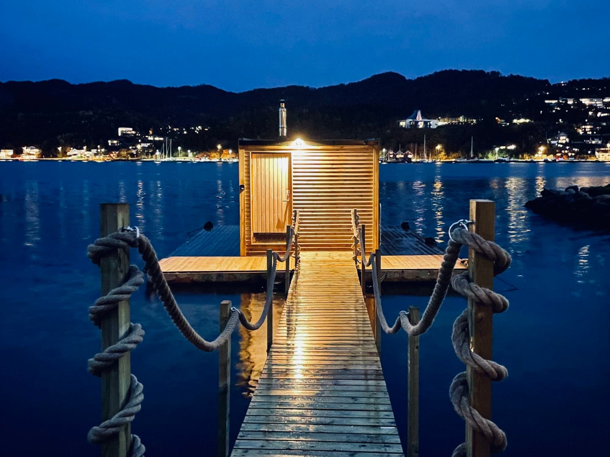 sauna and surroundings on floating deck with fjord and mountain views
