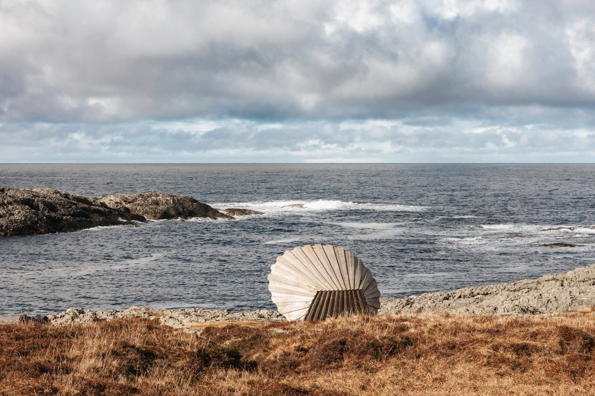 eit stort kamsjell som du kan sitte inni står vendt mot havet