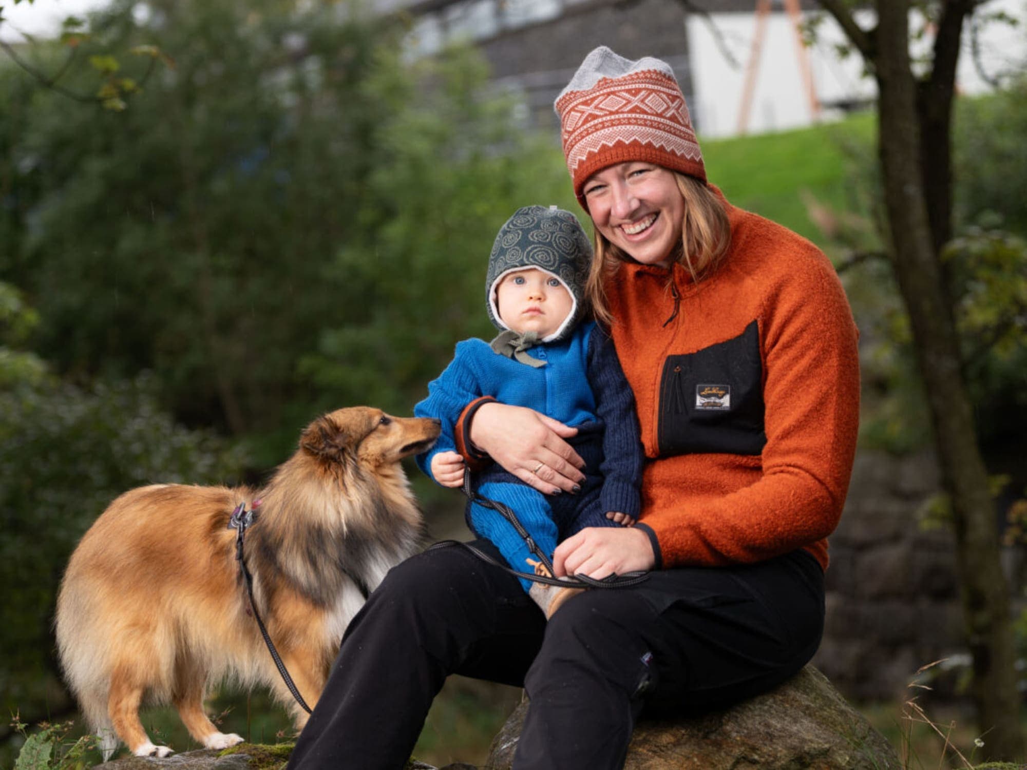 Mother and child with dog in nature sitting on a stone surrounded by trees