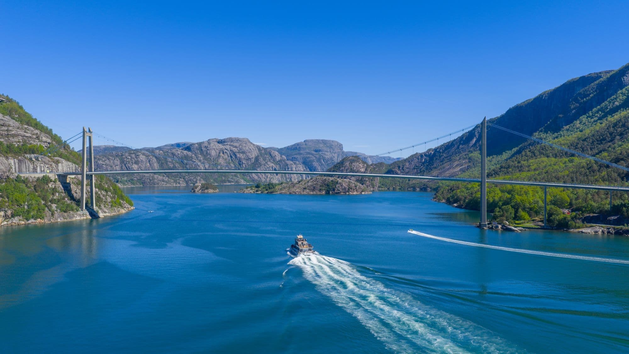 Sightseeing boat in the fjords, blue fjord and towering mountains
