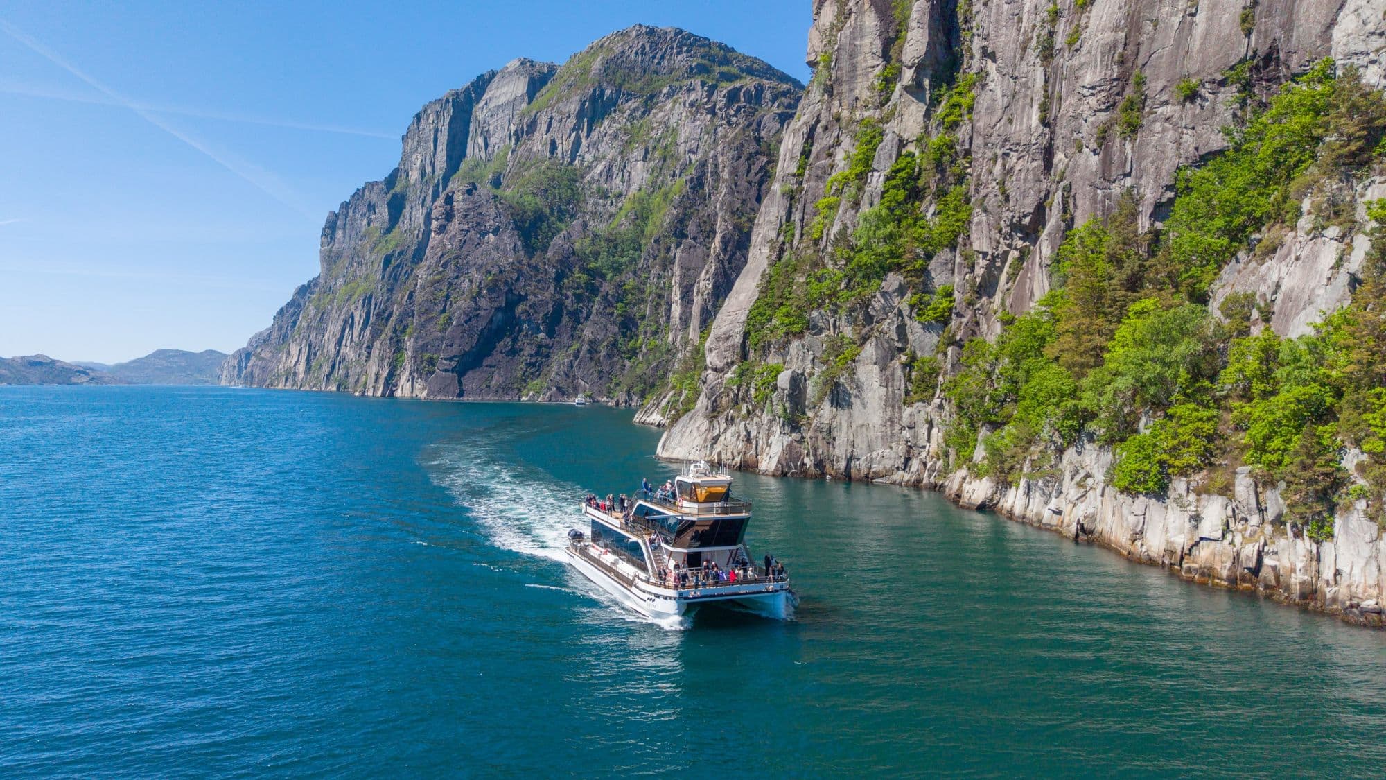 Sightseeing boat in the fjords, blue fjord and towering mountains